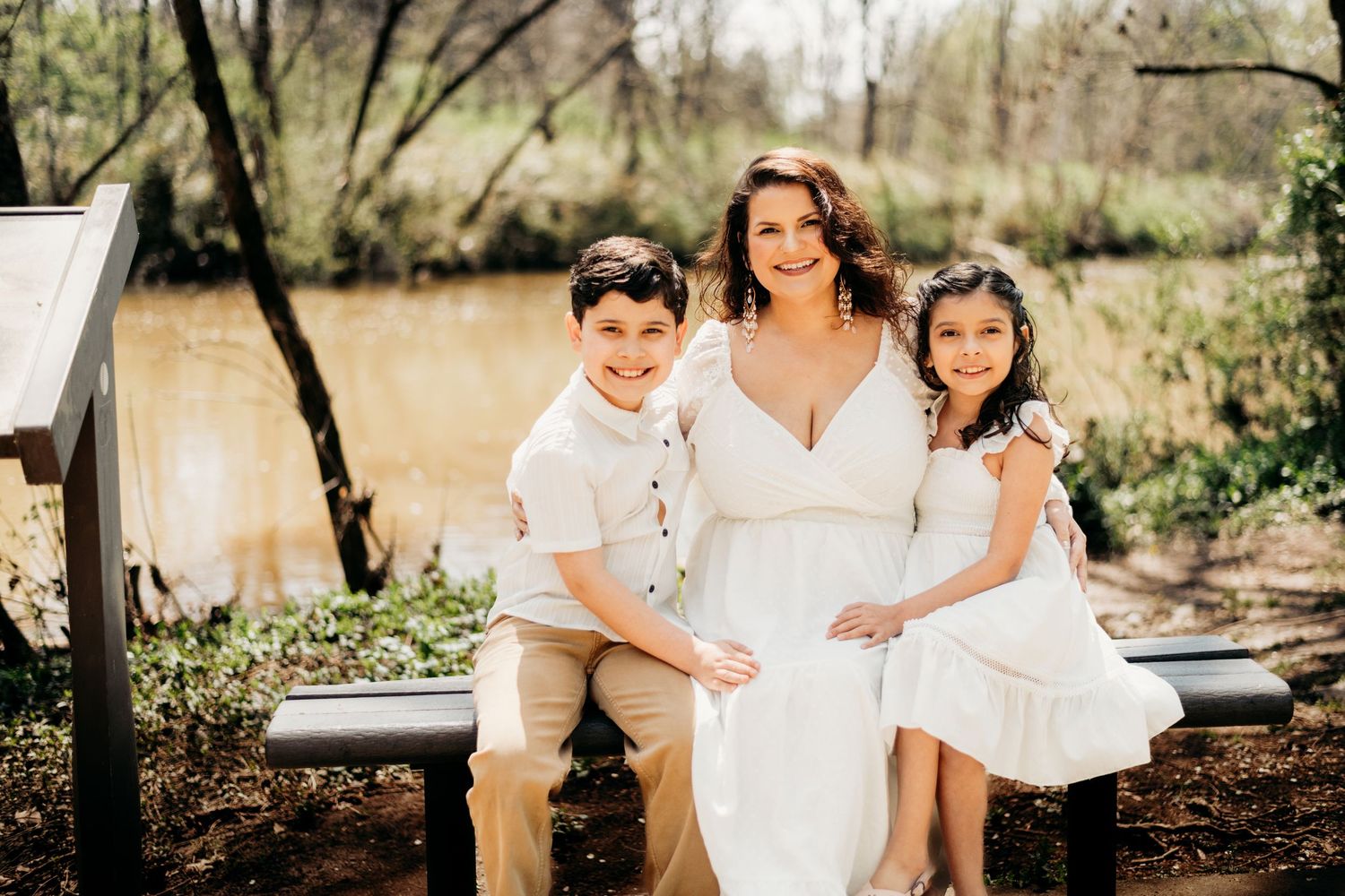 Family photoshoot in white outfits against natural outdoor backdrop.