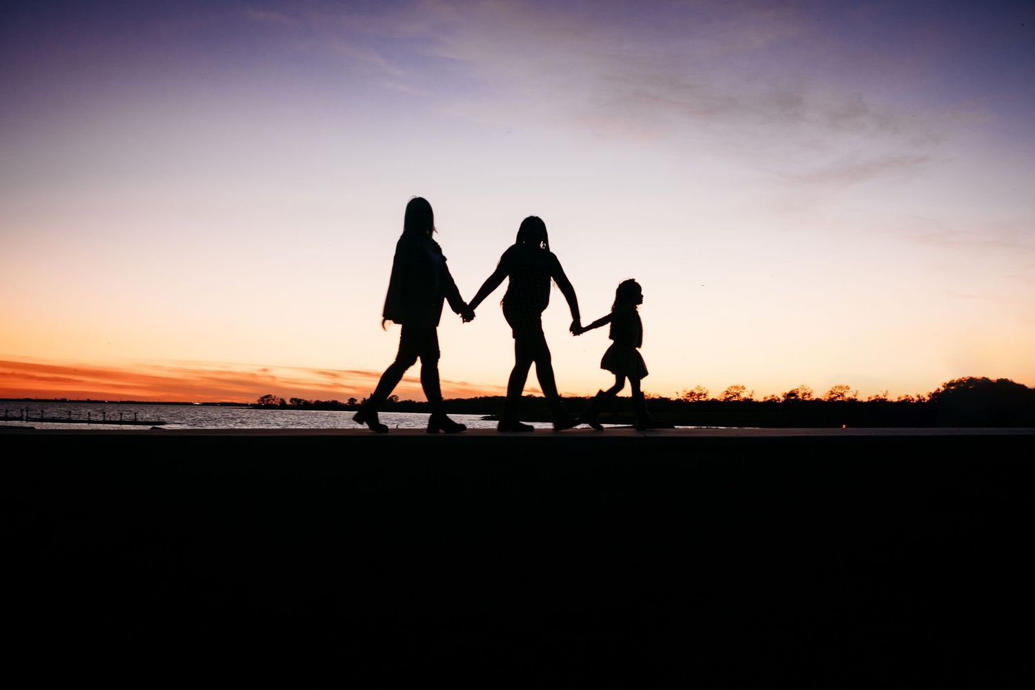 Silhouettes walking together against dramatic sunset sky.