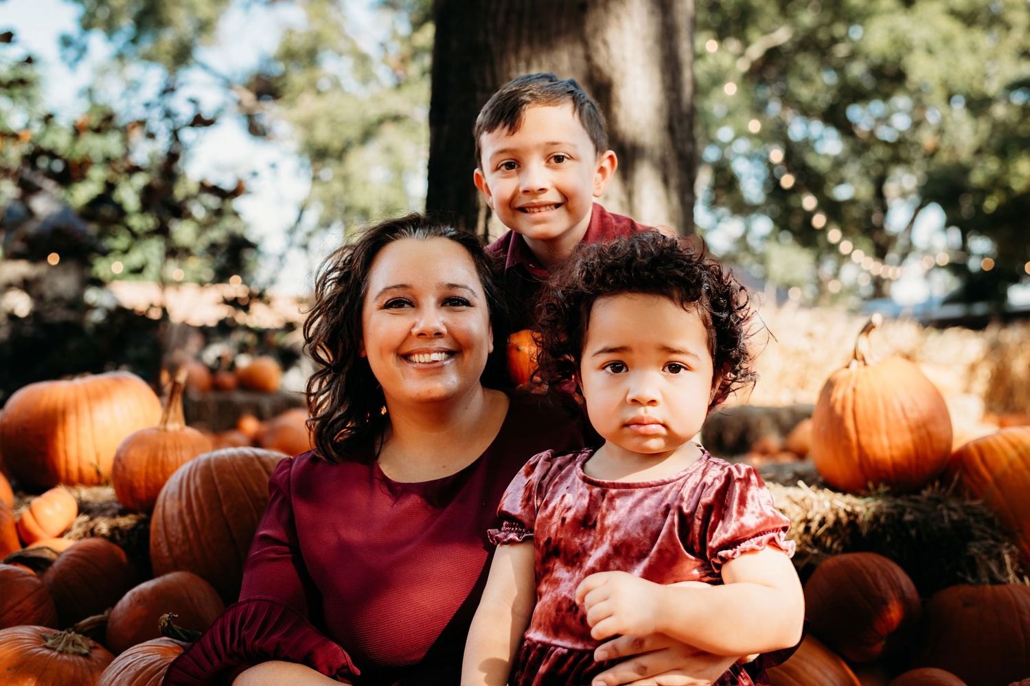 A fall scene with pumpkins and warm smiles captured in autumn sunlight.