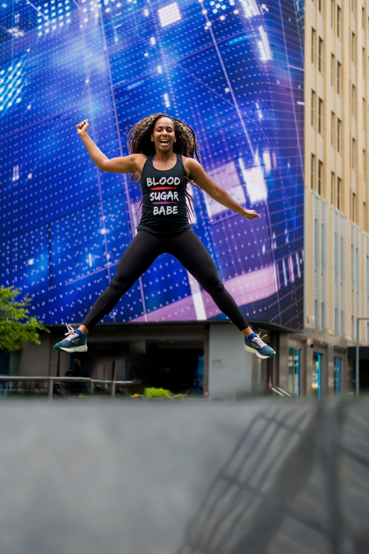 Dynamic jumping poses against blue digital display wall in urban setting.