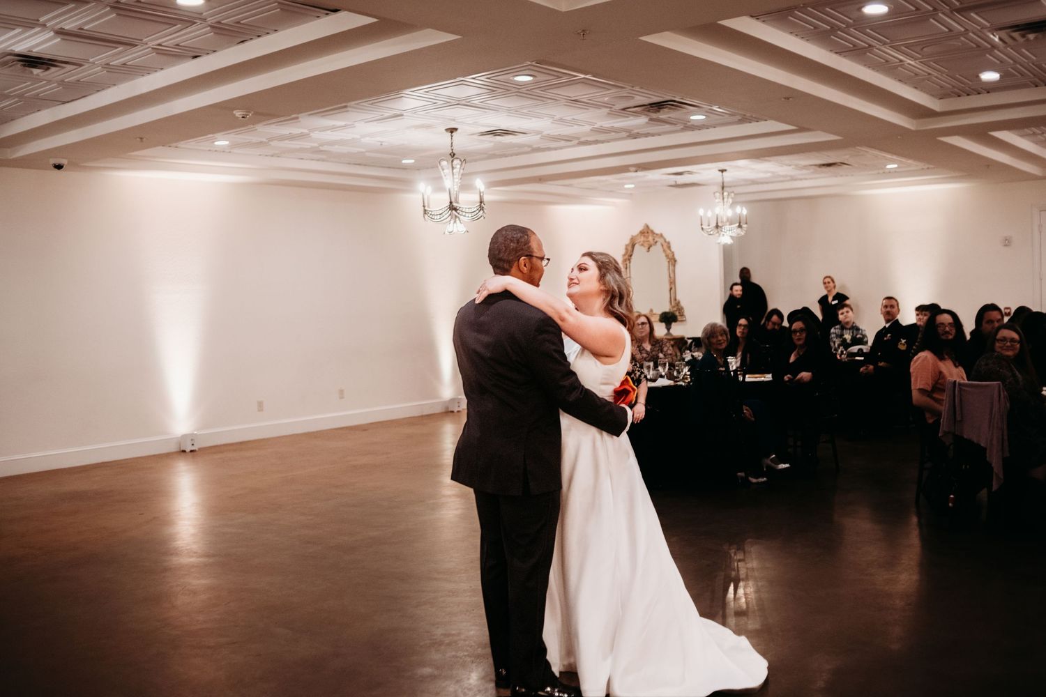 Couples dancing in an elegant ballroom with recessed lighting and modern decor.