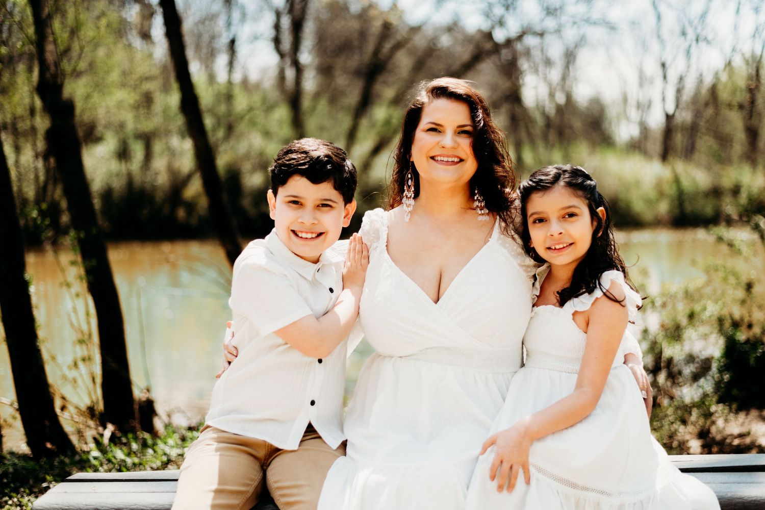 Family portrait session outdoors with coordinated white outfits in natural setting.