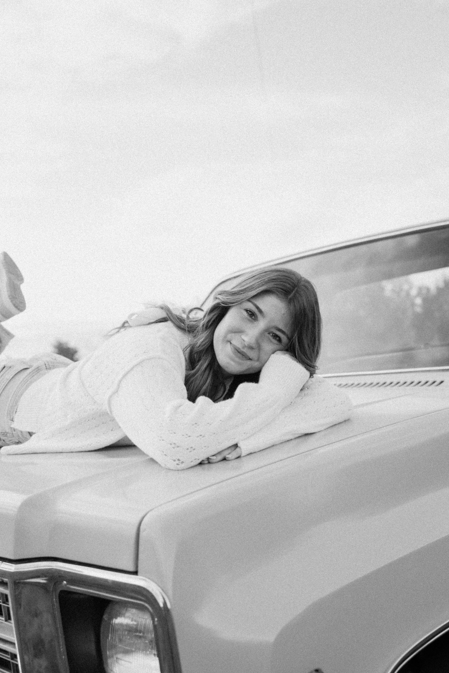 Black and white photo series showing someone resting their head on a vintage car in different relaxed poses.