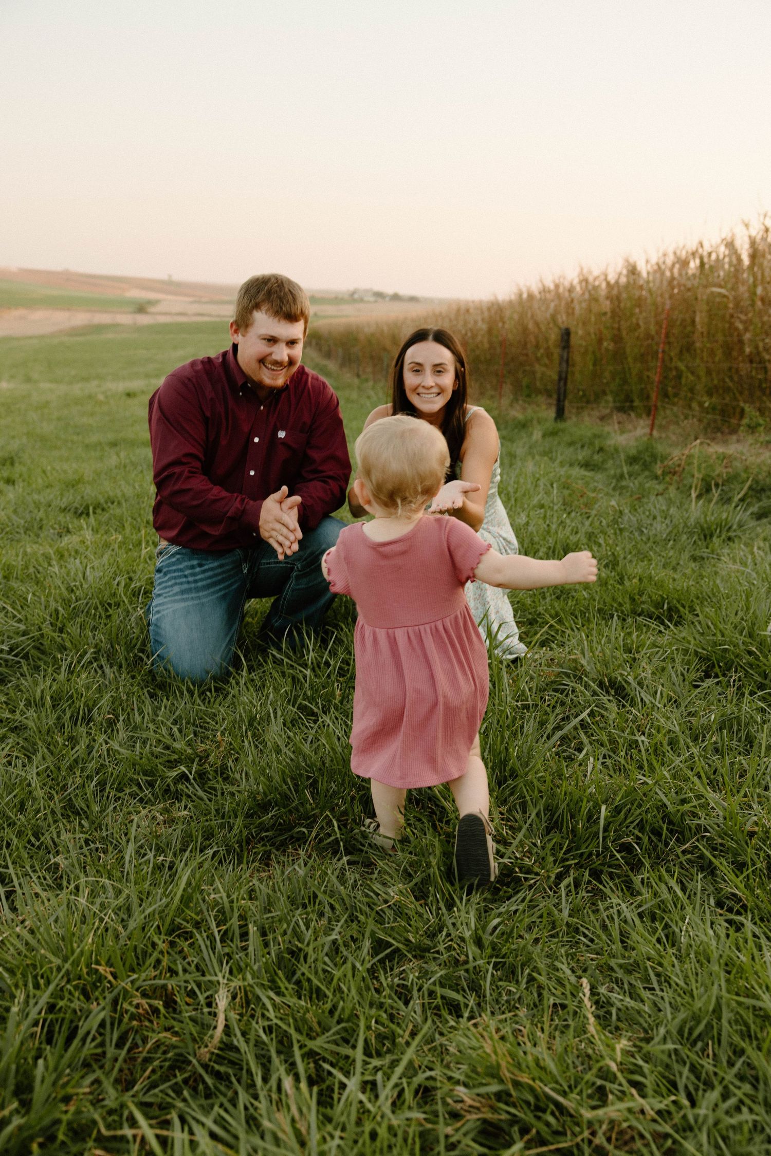 Family playing together in a lush green field during sunset.