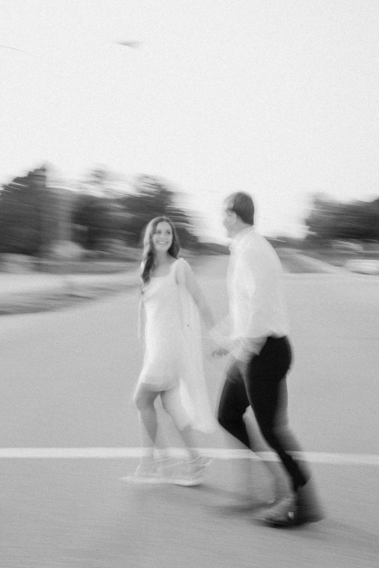 Black and white motion blur photo of couple dancing on a road.