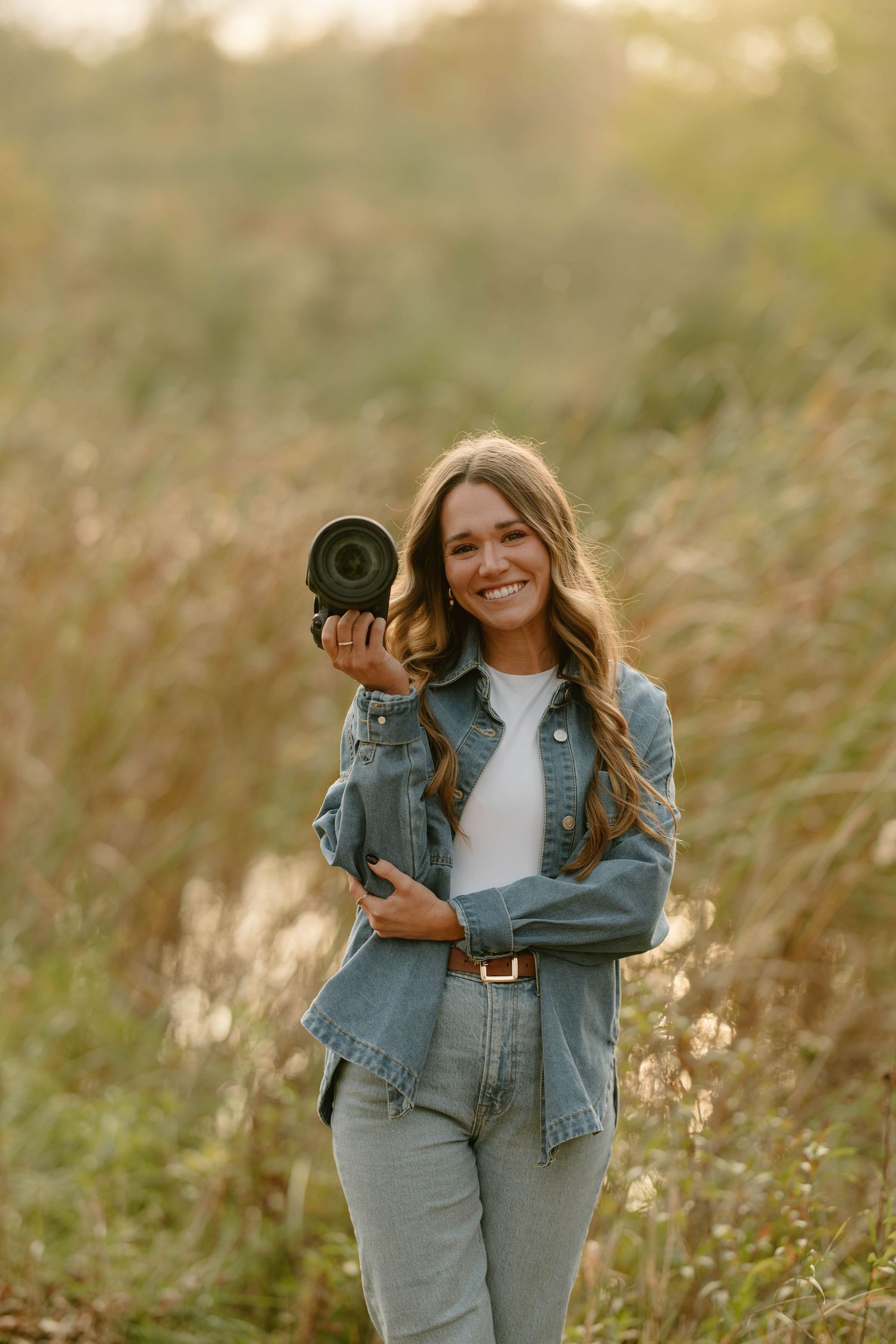 Photographers with cameras working in tall grass field during golden hour.