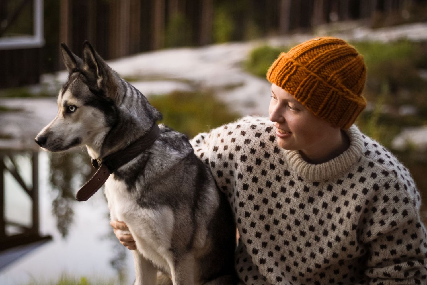 Dog and person in patterned sweater sitting outdoors.