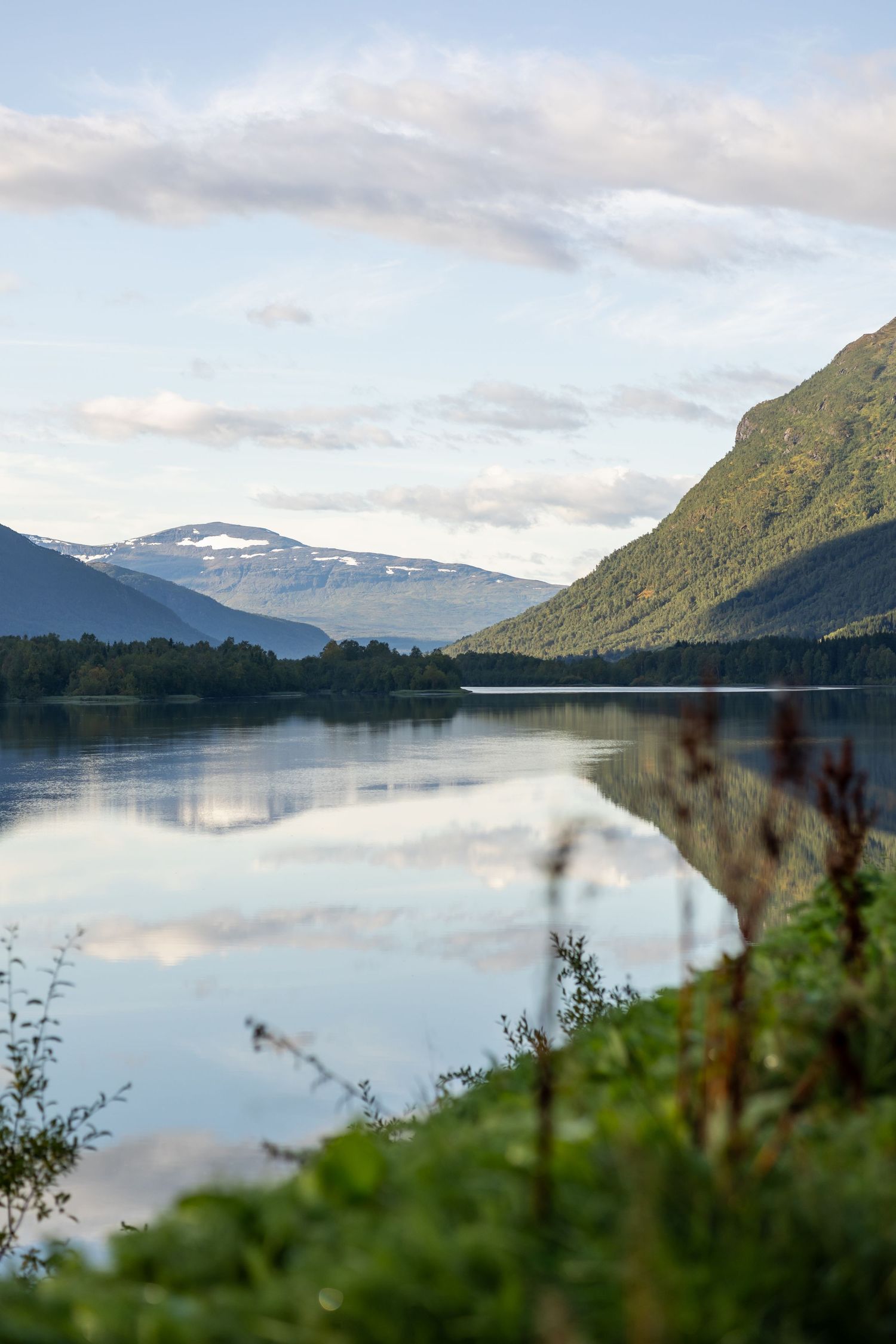Tranquil mountain lake reflecting cloudy skies and forested shoreline.