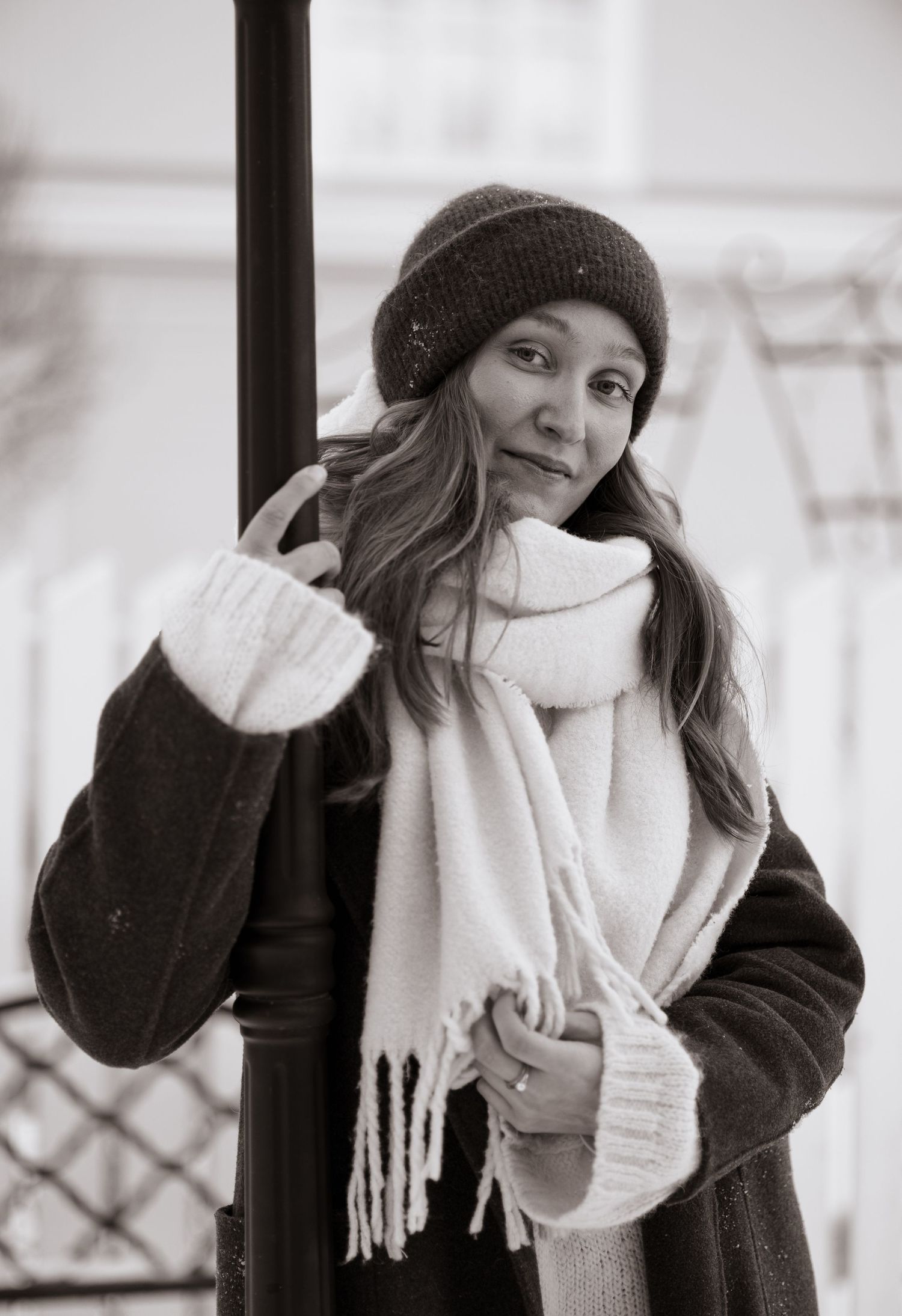 Person in winter attire with black coat and white scarf poses in monochrome series.