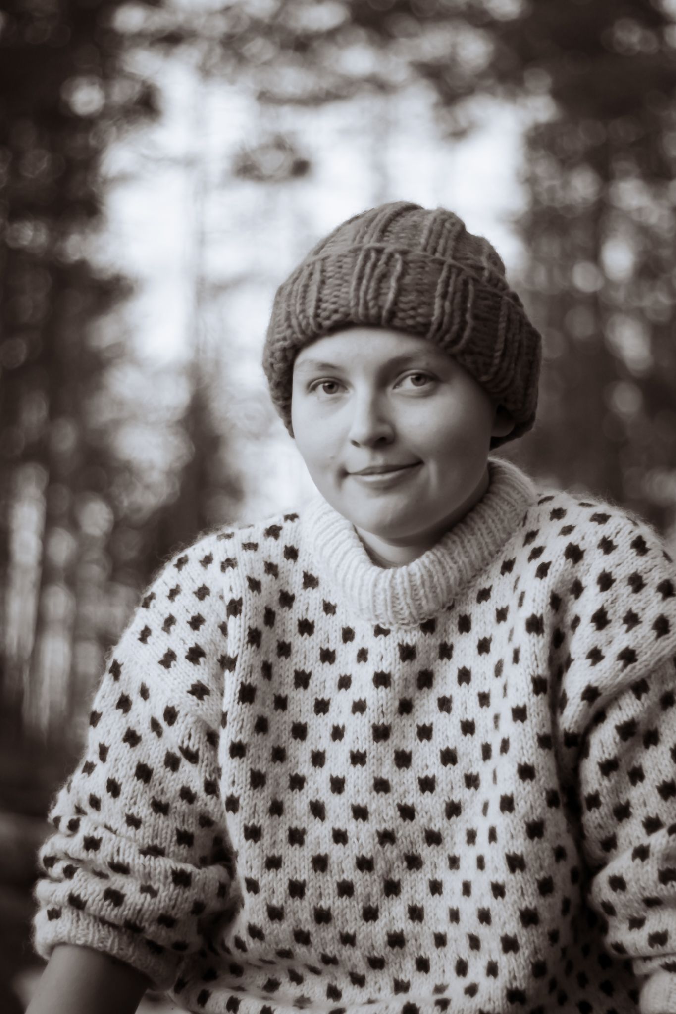 Mustavalkoinen muotokuva henkilöstä yllään kuviollinen neulepusero ja villapipo.