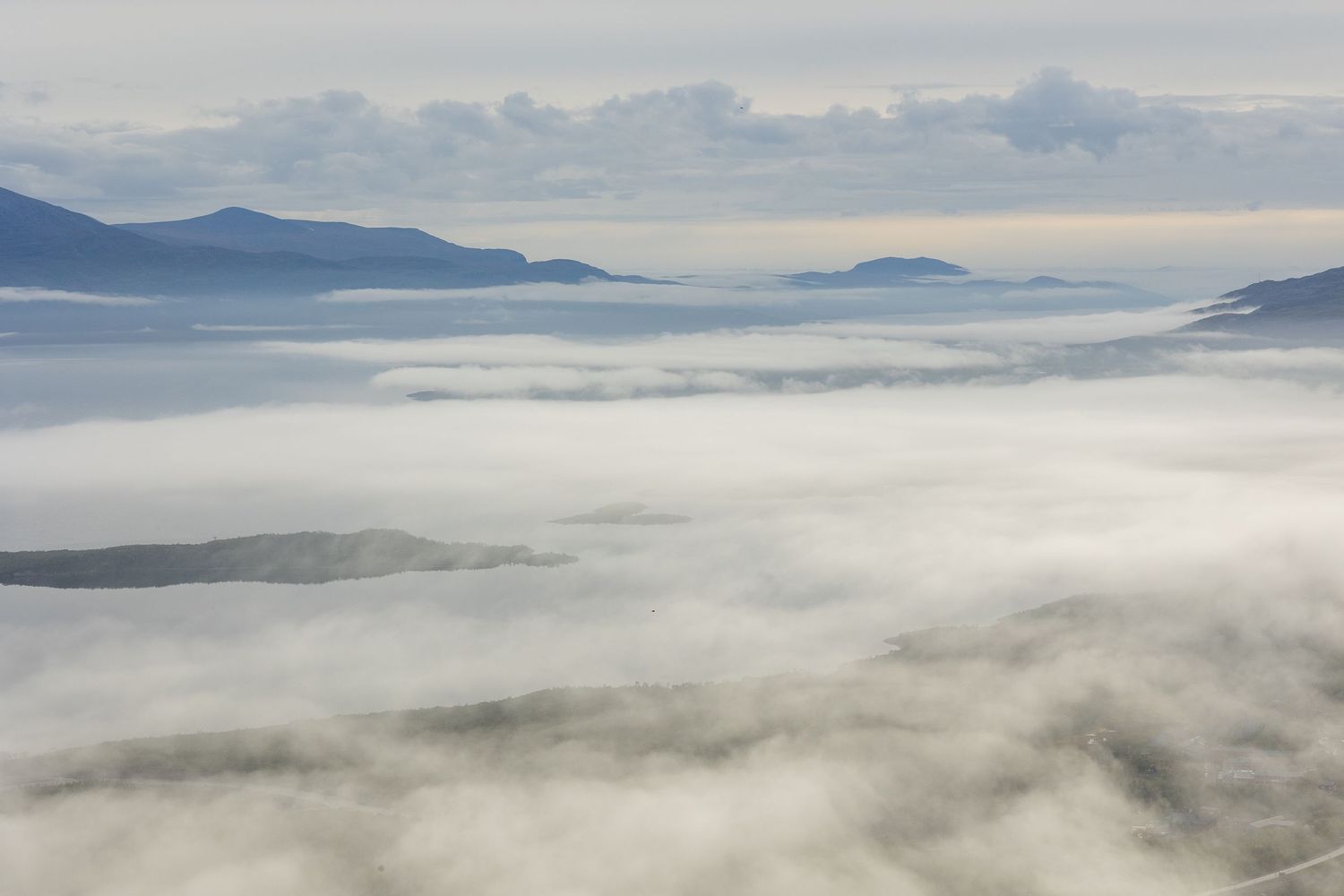 Rolling clouds blanket a mountain valley creating an ethereal sea of fog.