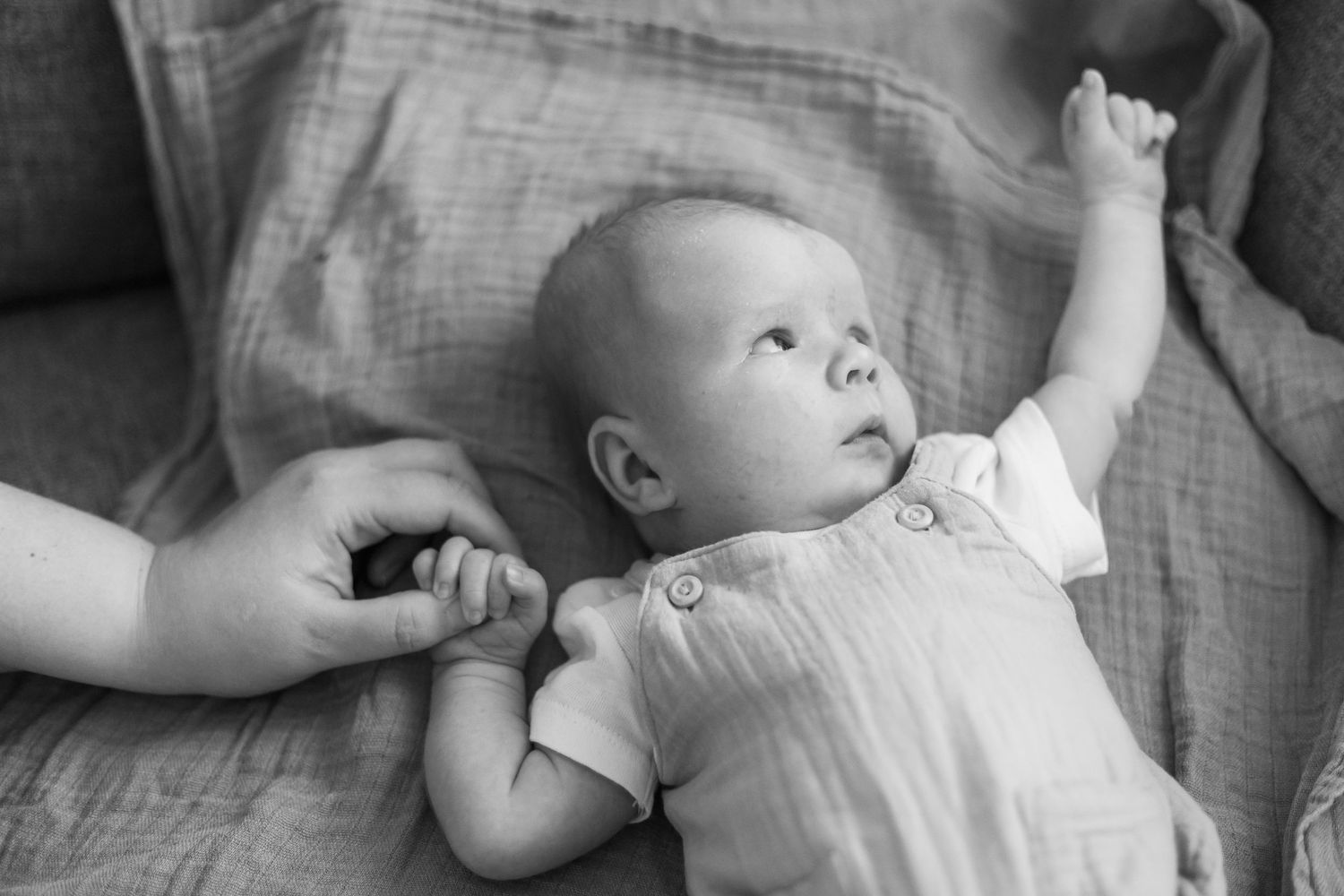 Close-up shots of infant lying on gray textured fabric in natural light.