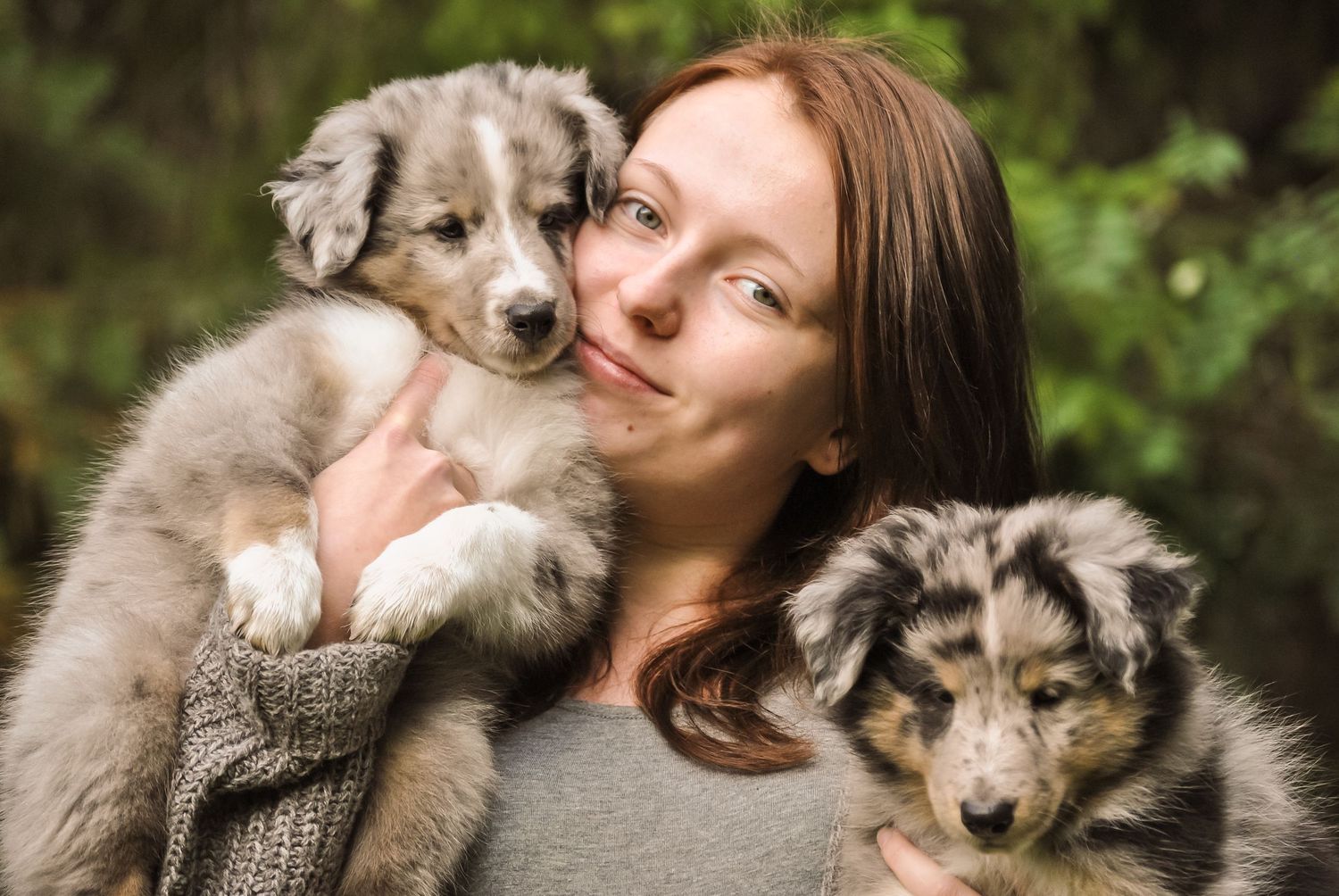 Lähikuva tytöstä sylissään kaksi koiranpentua.
