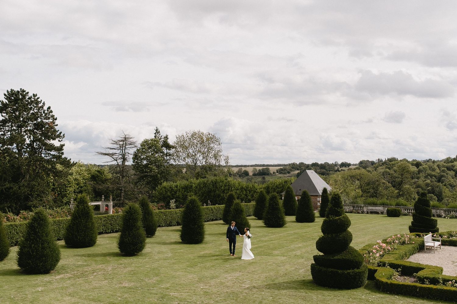 A scenic view of manicured gardens with trimmed topiary bushes under cloudy skies.