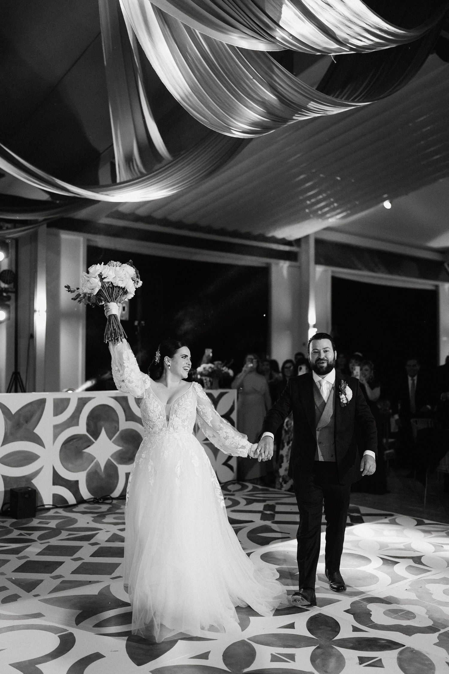 Wedding reception venue with elegant white draping and patterned dance floor.