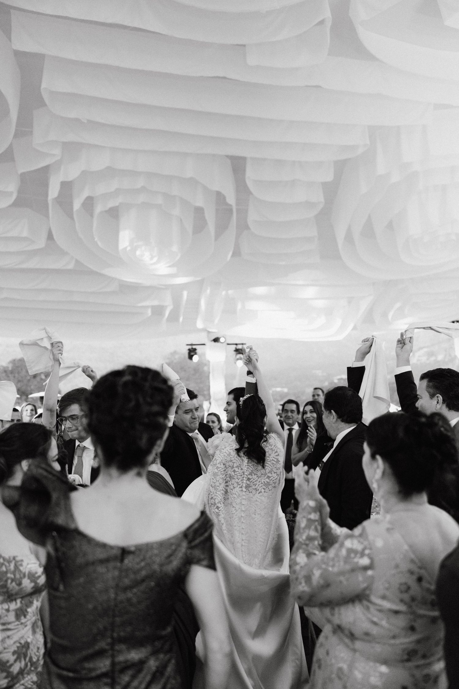 Wedding reception venue with white draped ceiling and guests celebrating on the dance floor.