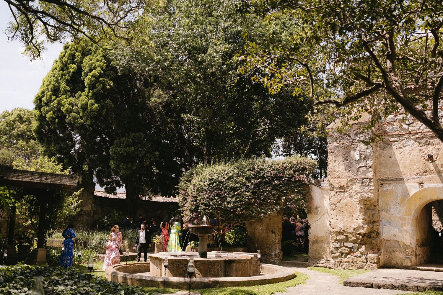 Historic stone courtyard with arched doorways and lush greenery in a Mediterranean setting.