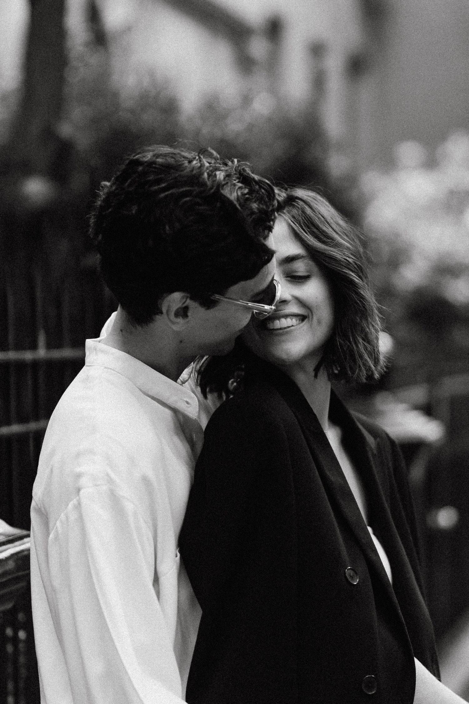 A romantic couple embraces while wearing contrasting black and white outfits on a city street.