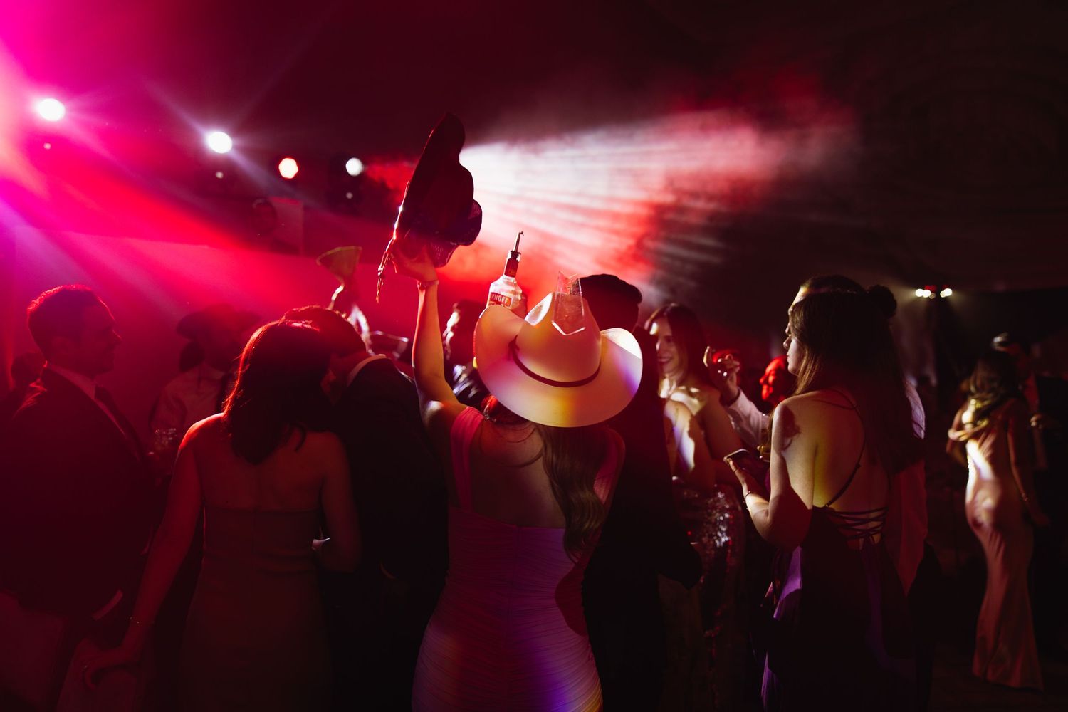 Wedding reception dance floor illuminated by vibrant red lighting with party decorations.
