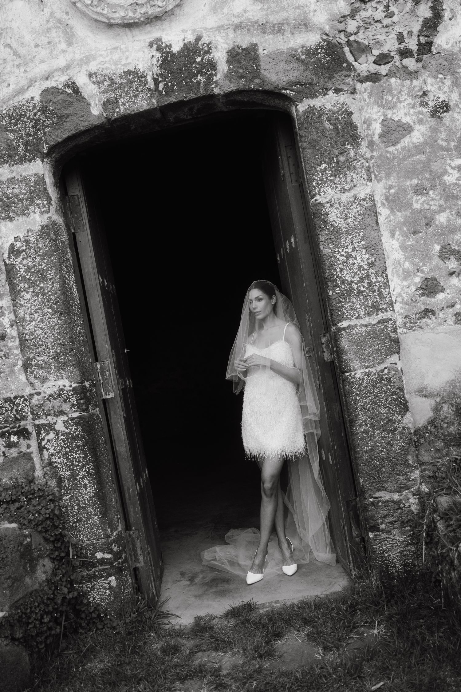 A sequence of black and white photos showing a figure in white moving through a stone doorway.