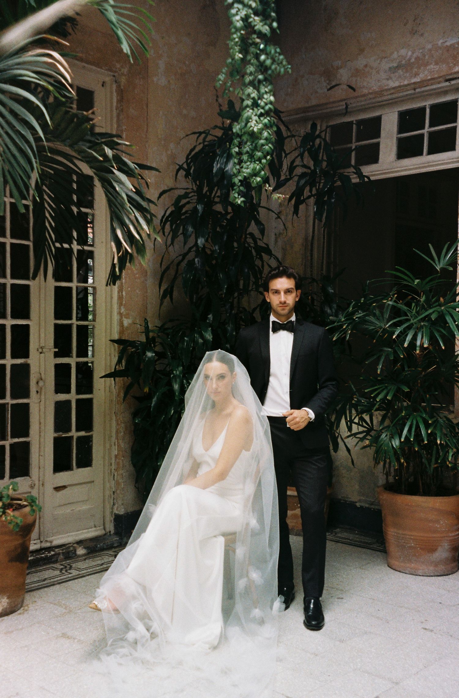 Elegant wedding portrait in tropical courtyard with potted palms.