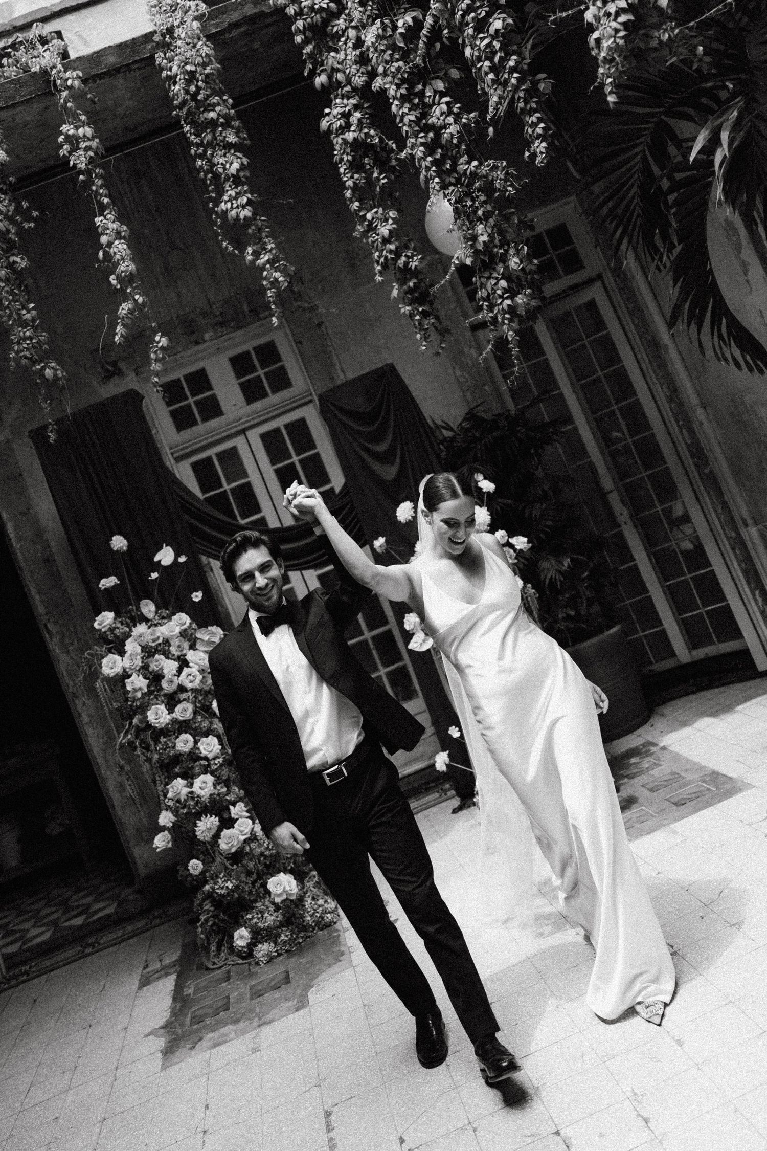 Black and white wedding dance sequence captured in a courtyard with climbing roses and French doors.