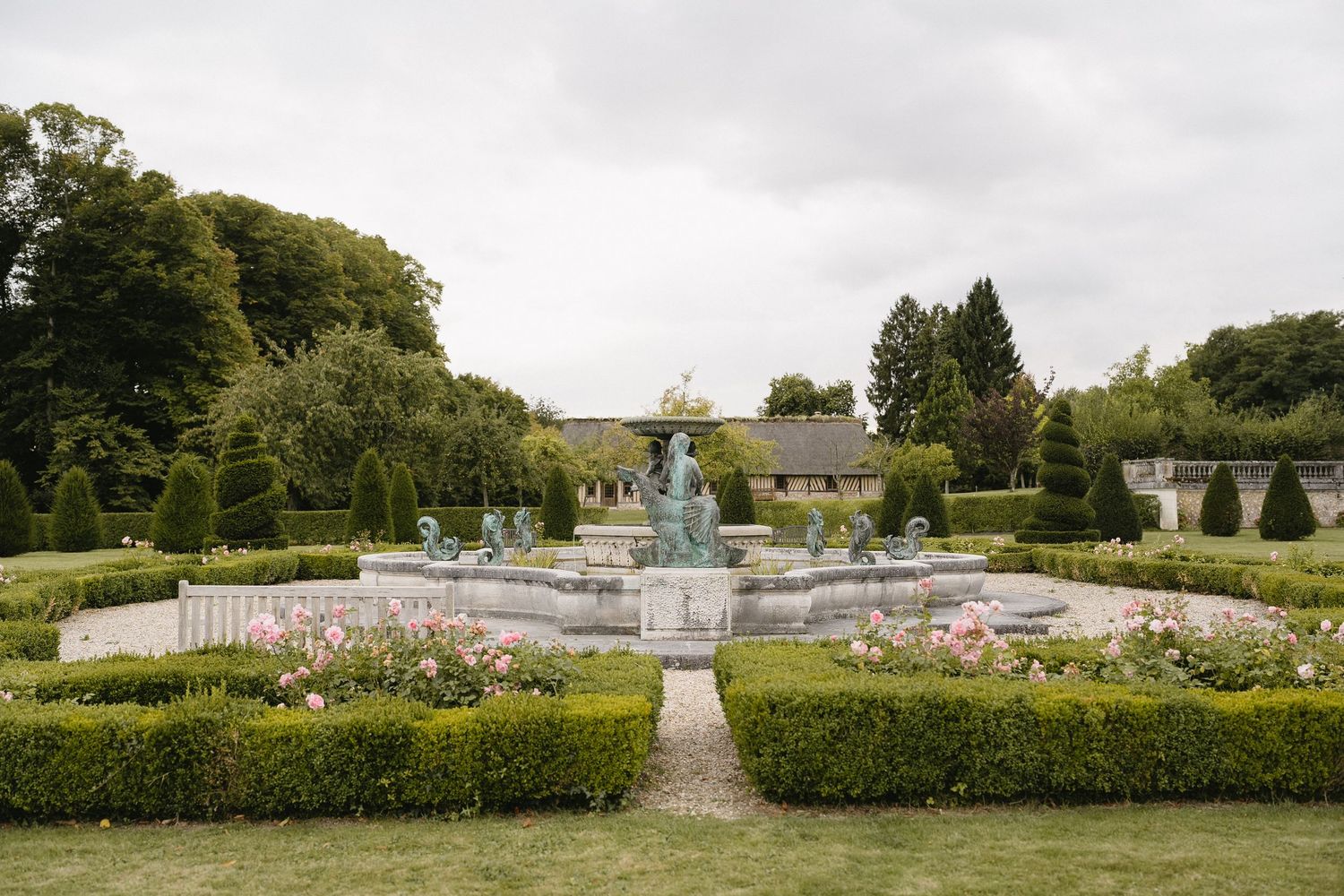 Expansive formal garden with symmetrical pathways and manicured hedges under cloudy sky.
