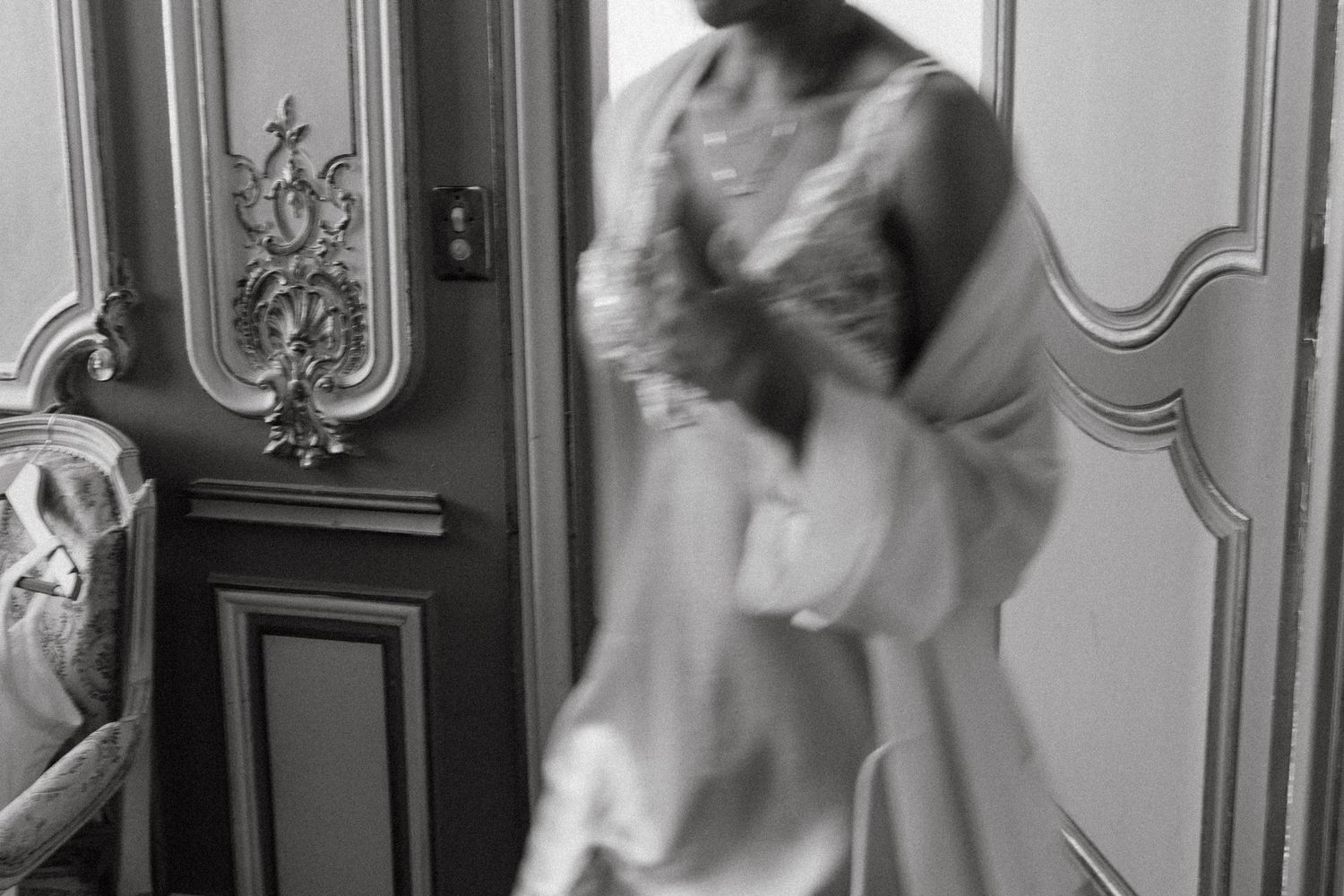 Motion-blurred figure in white moving through an ornately decorated interior space.