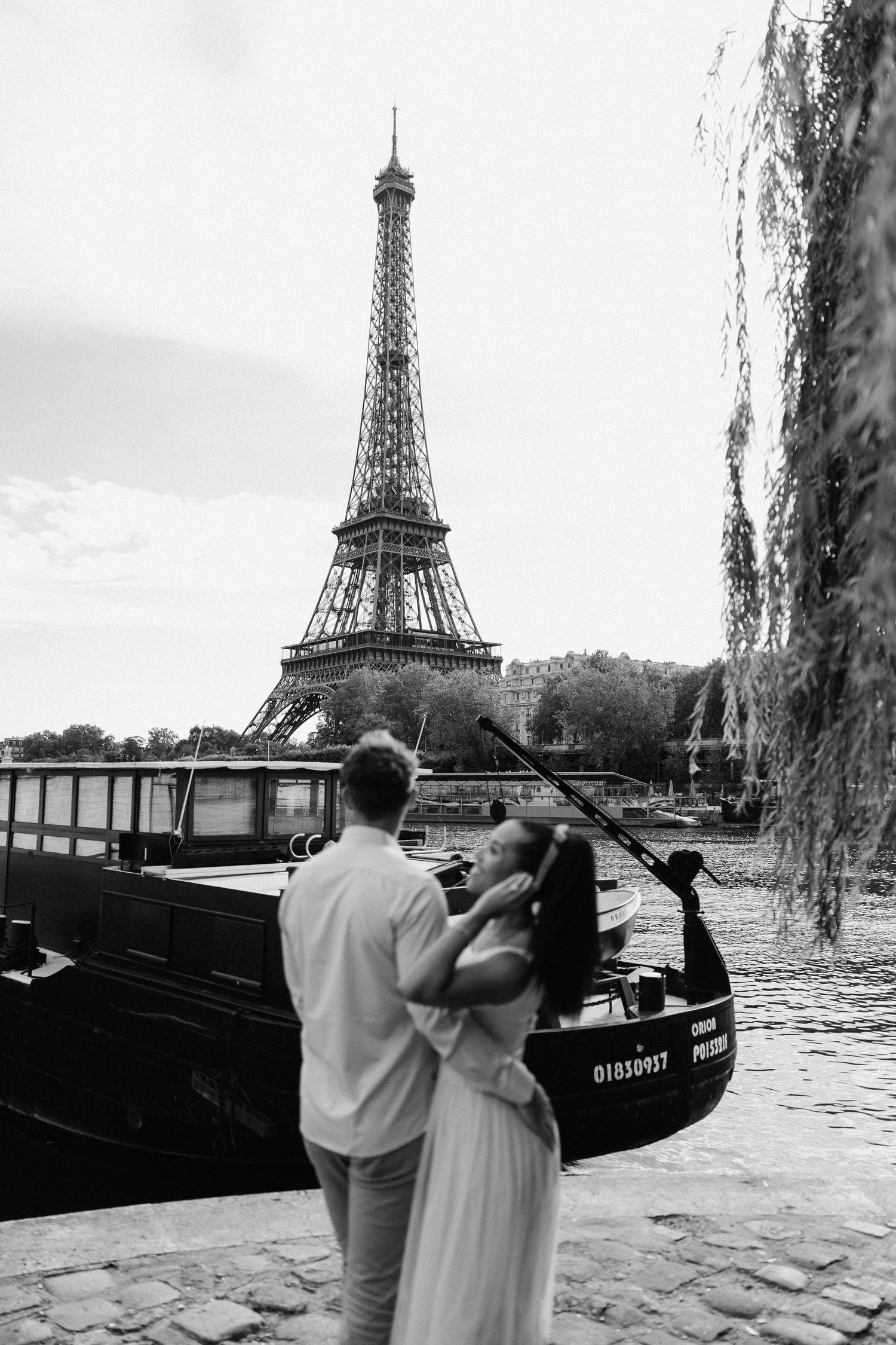 Couple sharing intimate moments along Seine River with Eiffel Tower views.