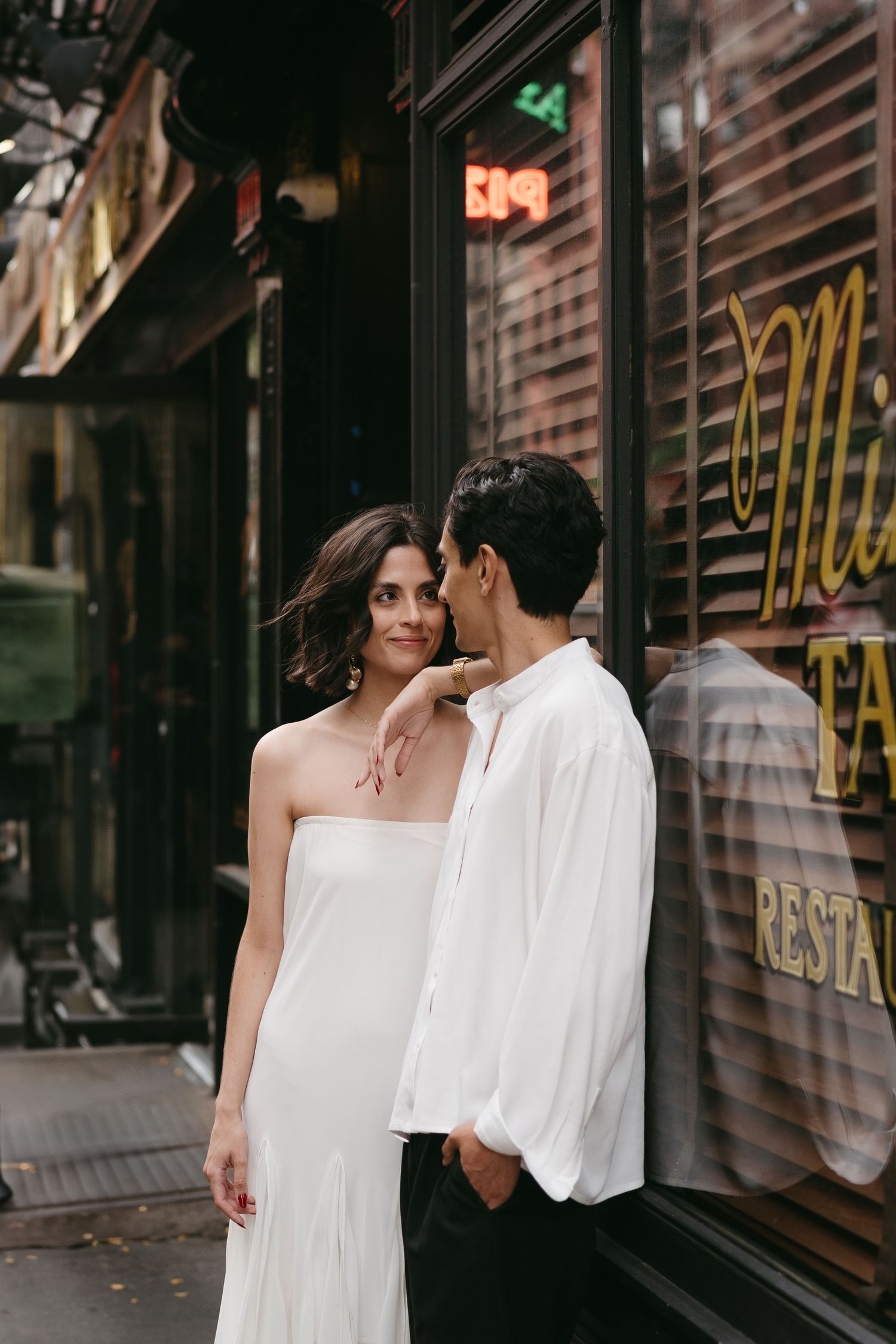 Intimate urban portrait against storefront window in black and white.