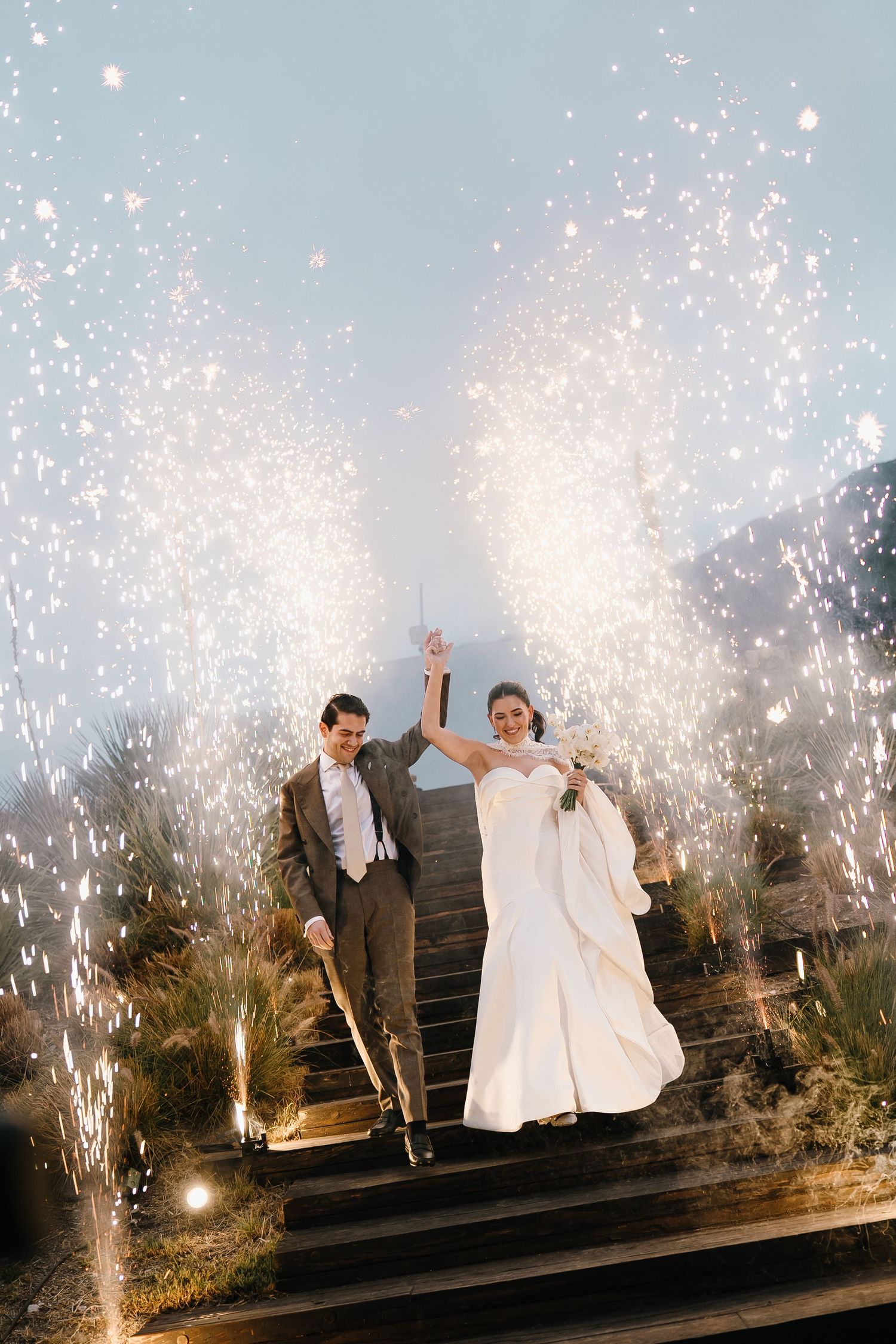 A celebratory moment on stairs with sparklers creating a magical wedding exit.