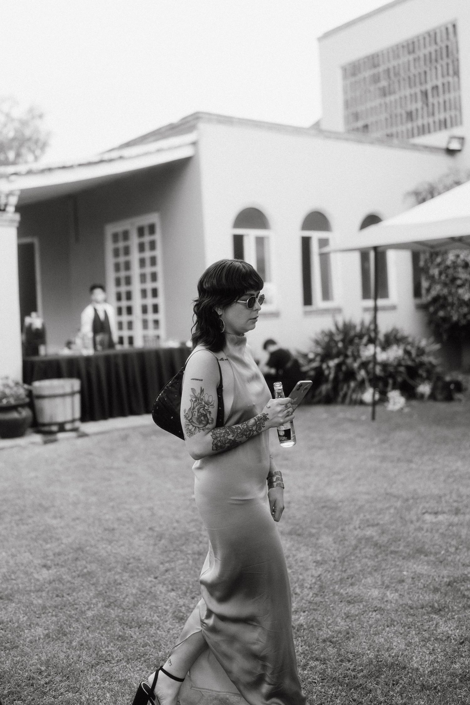 A candid black and white photo of someone walking across a grassy lawn.