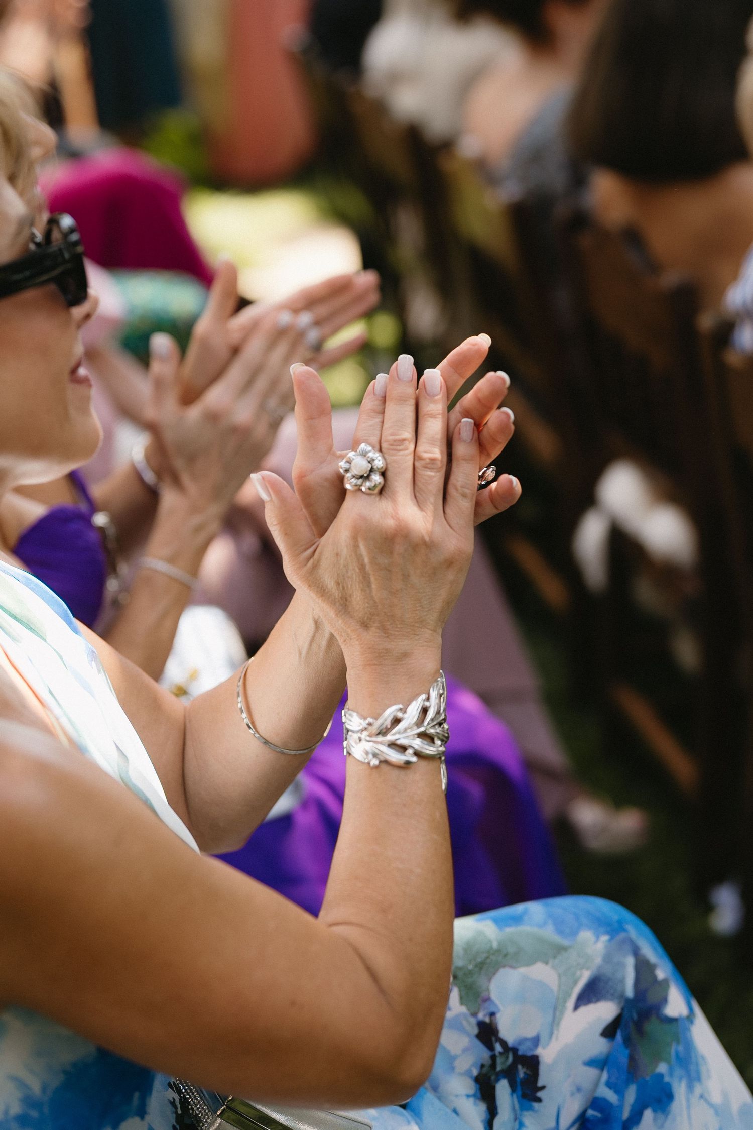 Wedding guests clapping hands in celebration wearing colorful formal attire.