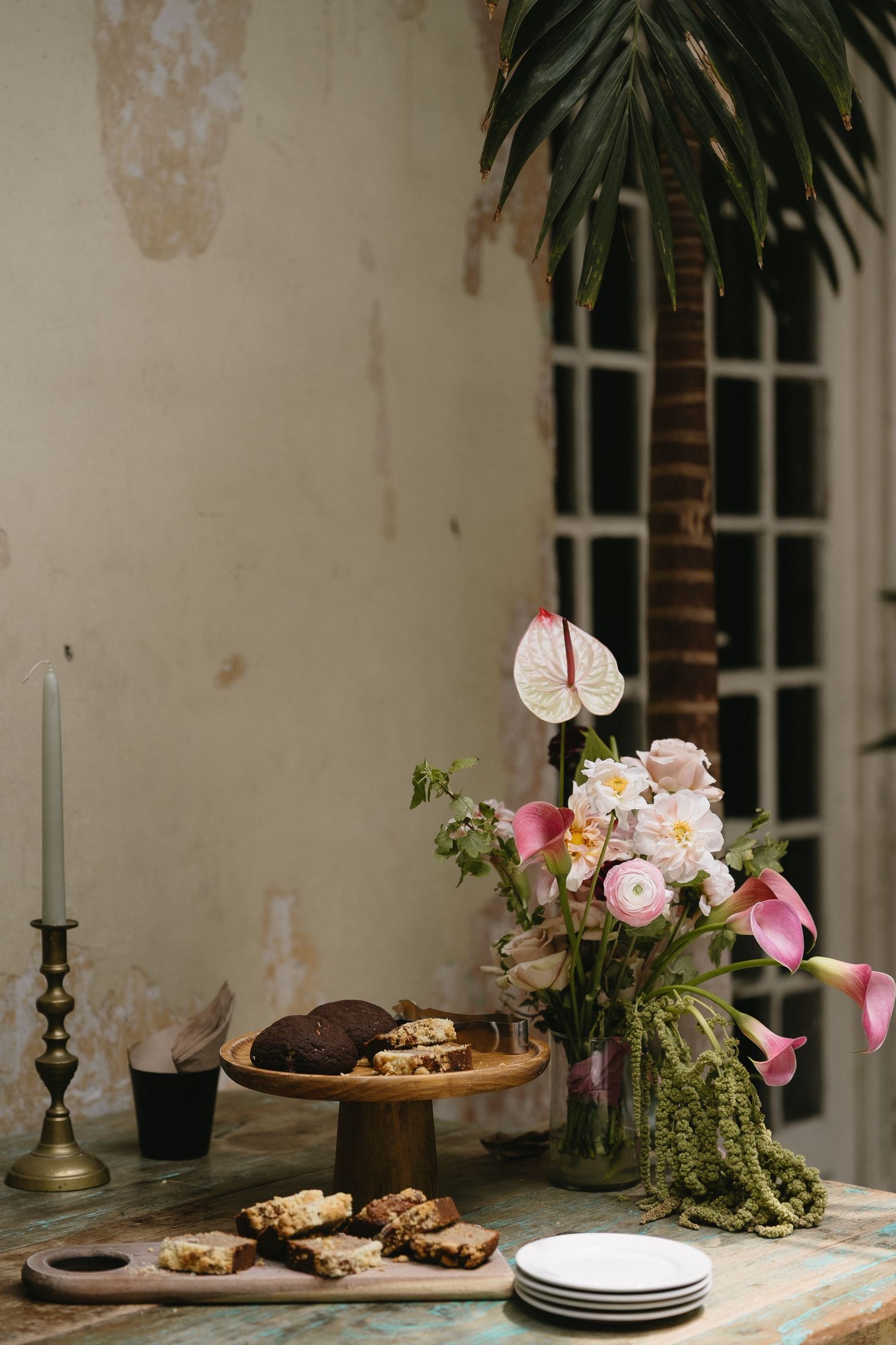 Rustic table display with desserts, plates, and delicate pink flower arrangements.