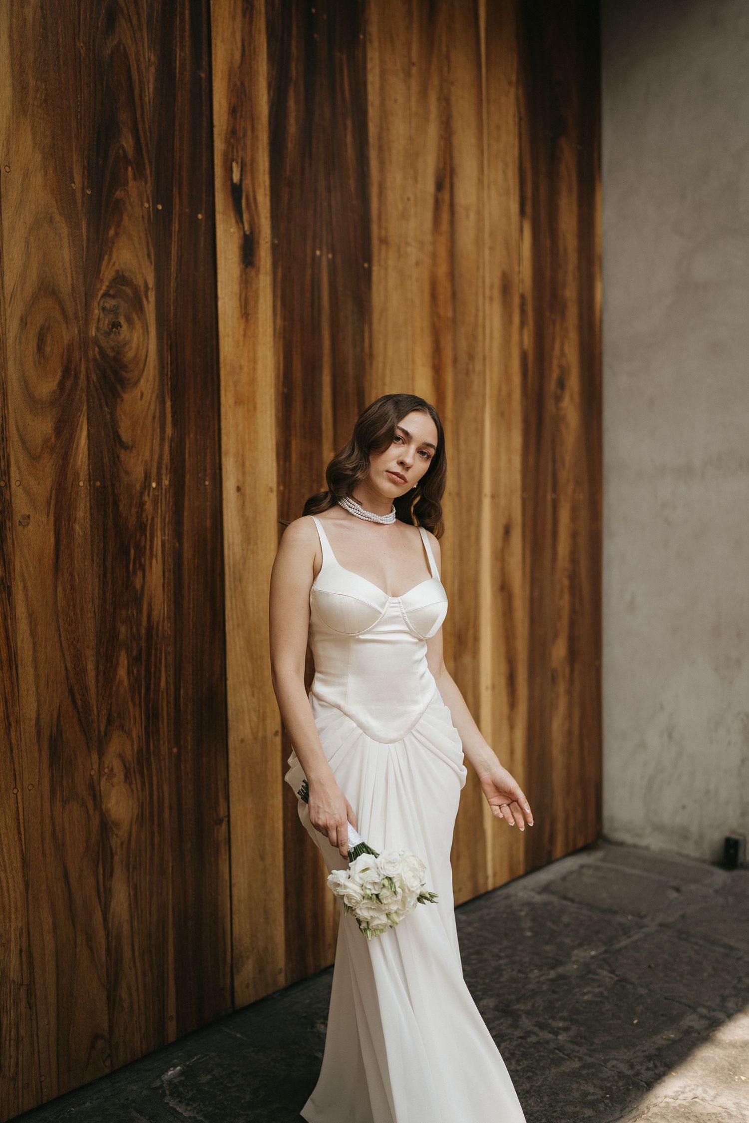 A white wedding dress contrasts beautifully against dark wooden doors in an artistic series.