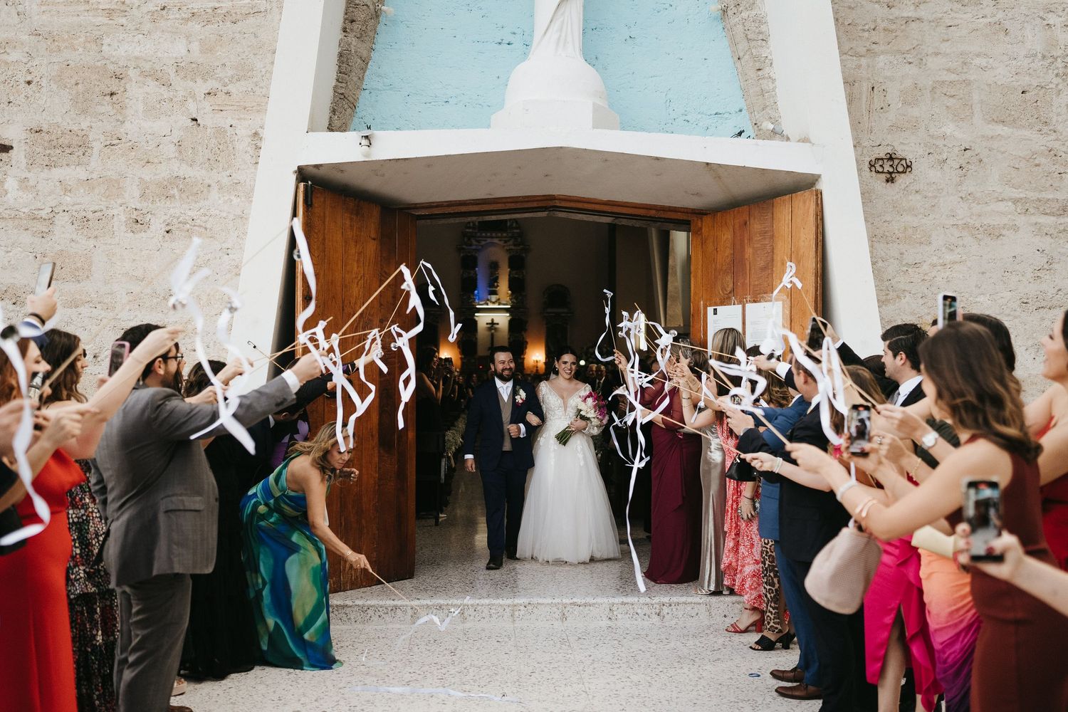 Wedding celebration in a grand hall with guests raising their arms in celebration.