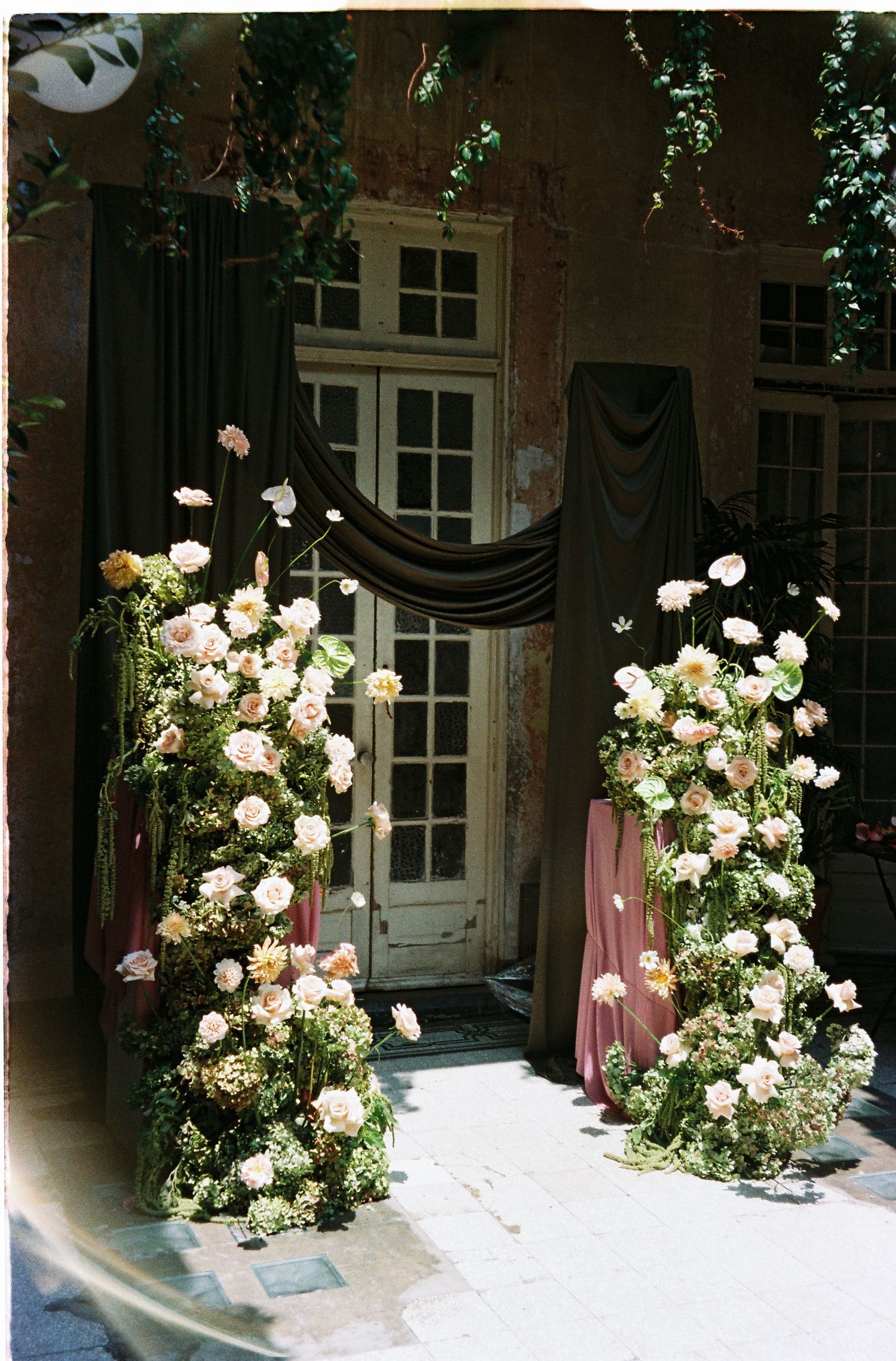 Romantic floral installation with white and pink roses adorning a doorway entrance.