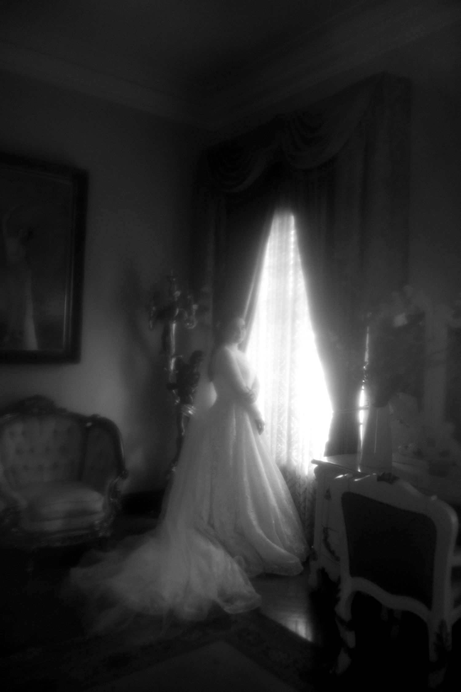 A ghostly figure in a white dress appears in a dark room with dramatic lighting through a window.