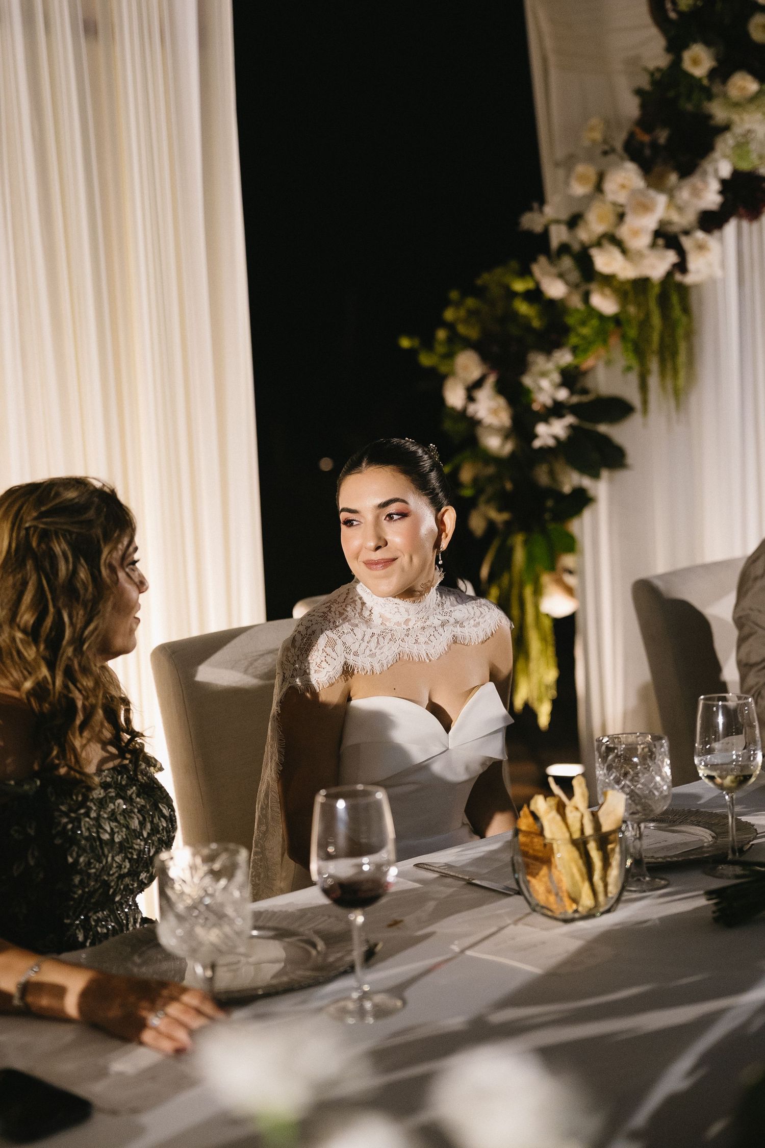 Elegant wedding reception table setting with white linens, wine glasses and floral centerpieces.