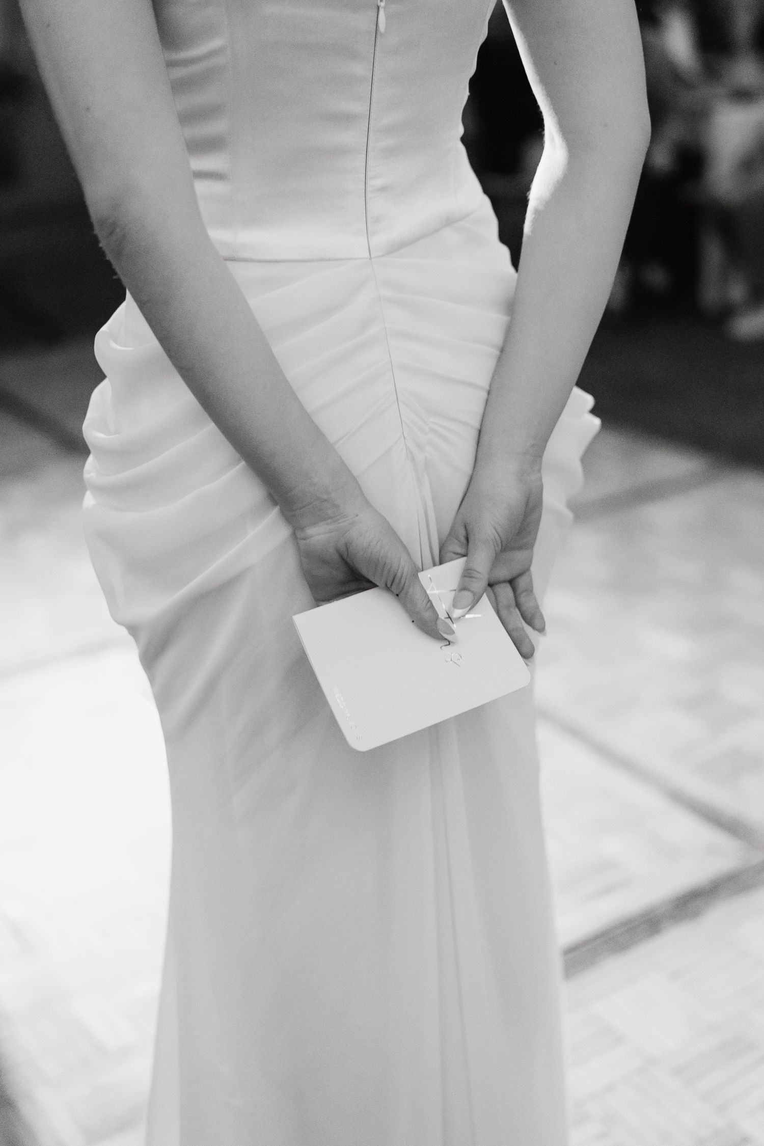Close-up detail of white wedding dress showing elegant fabric and tailoring.