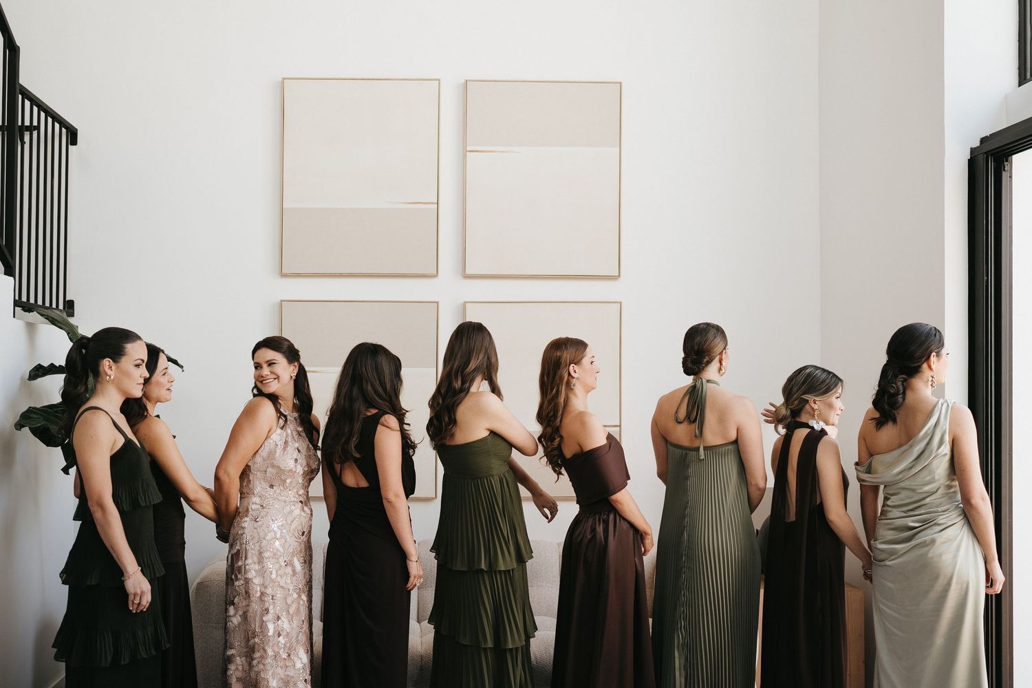 Artistic lineup of wedding party members against white wall.