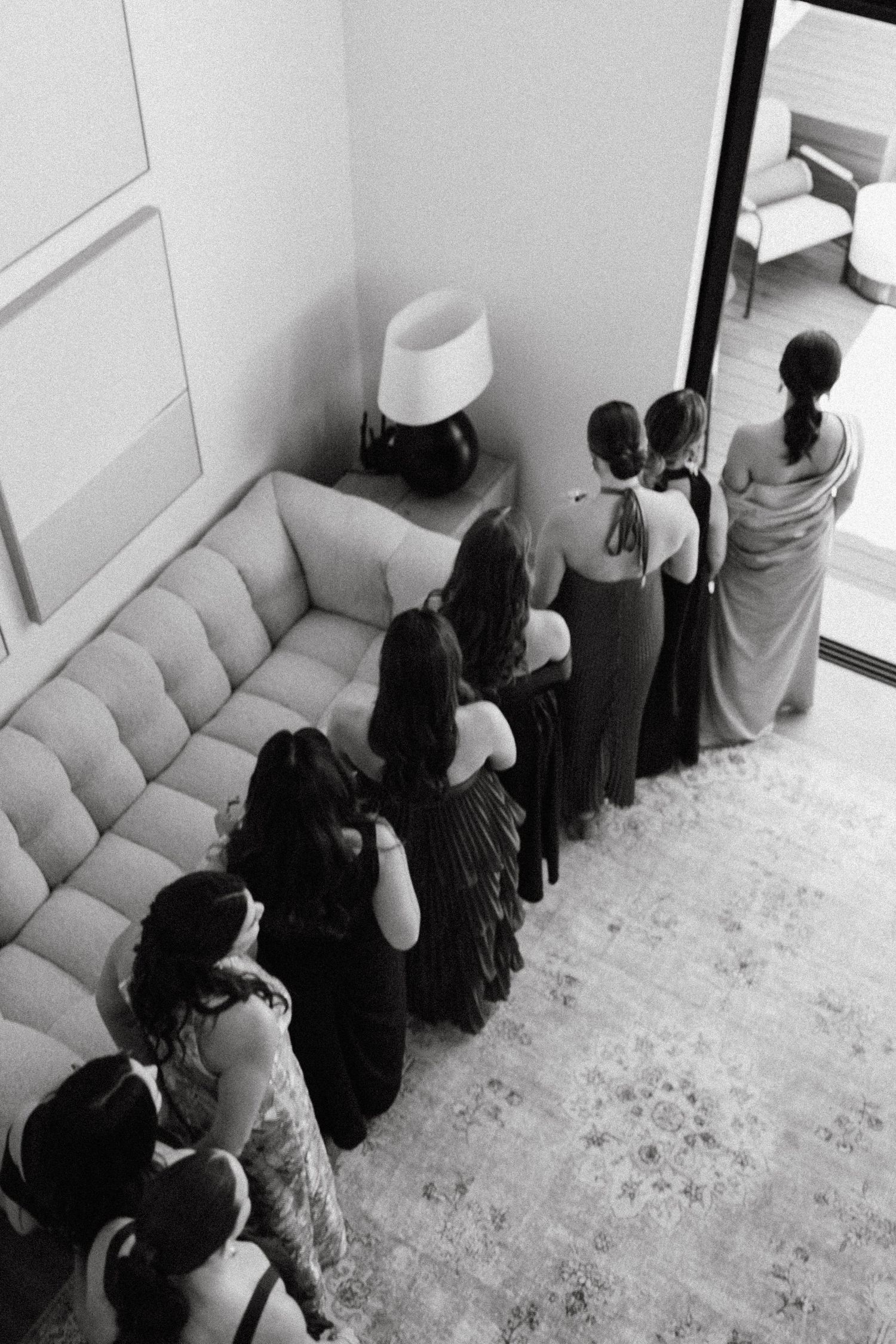 Group of people standing in a modern room with white walls and plush seating.