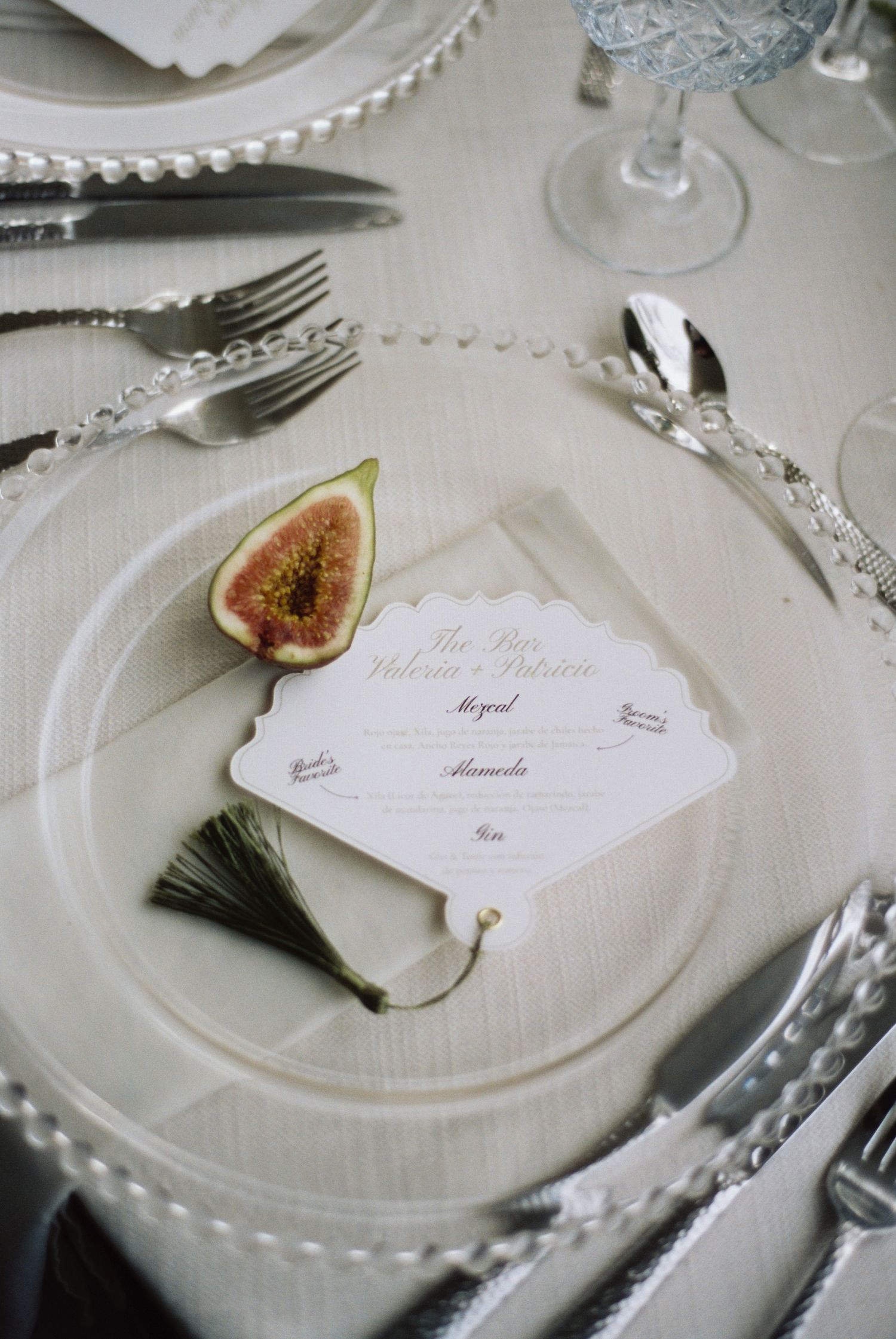 Elegant place settings with name cards and fresh figs on white plates at a formal dining table.