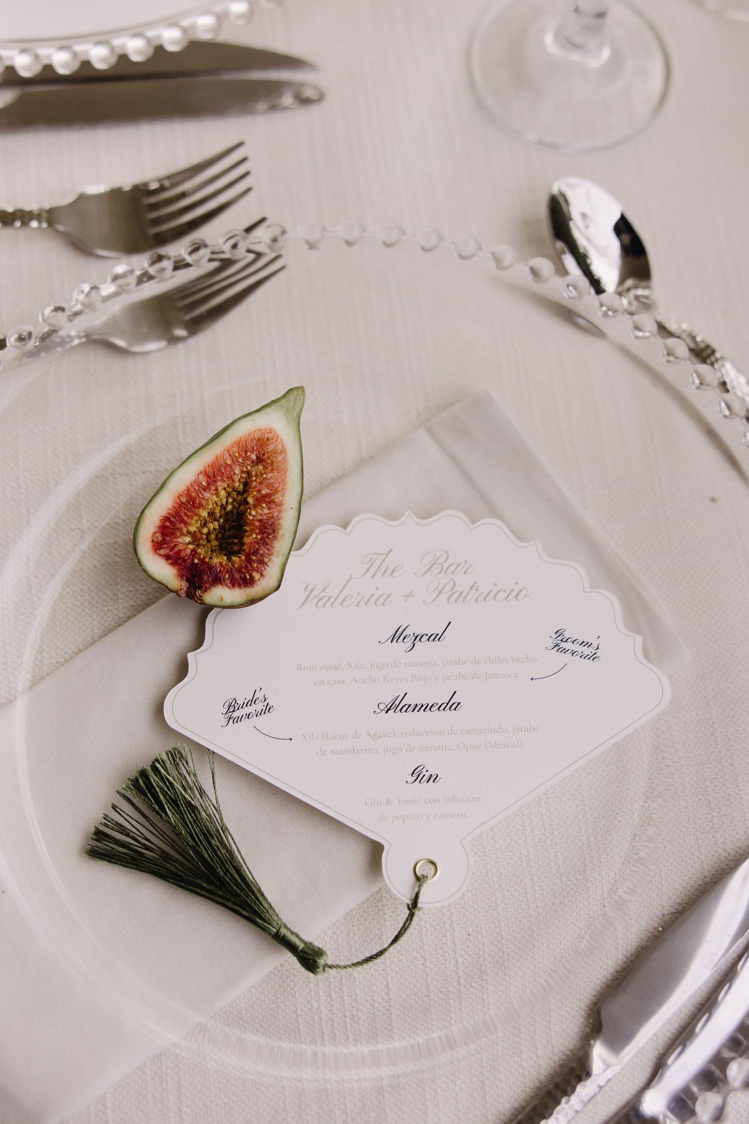 Elegant place setting with fig garnish, silverware and scalloped white name card.