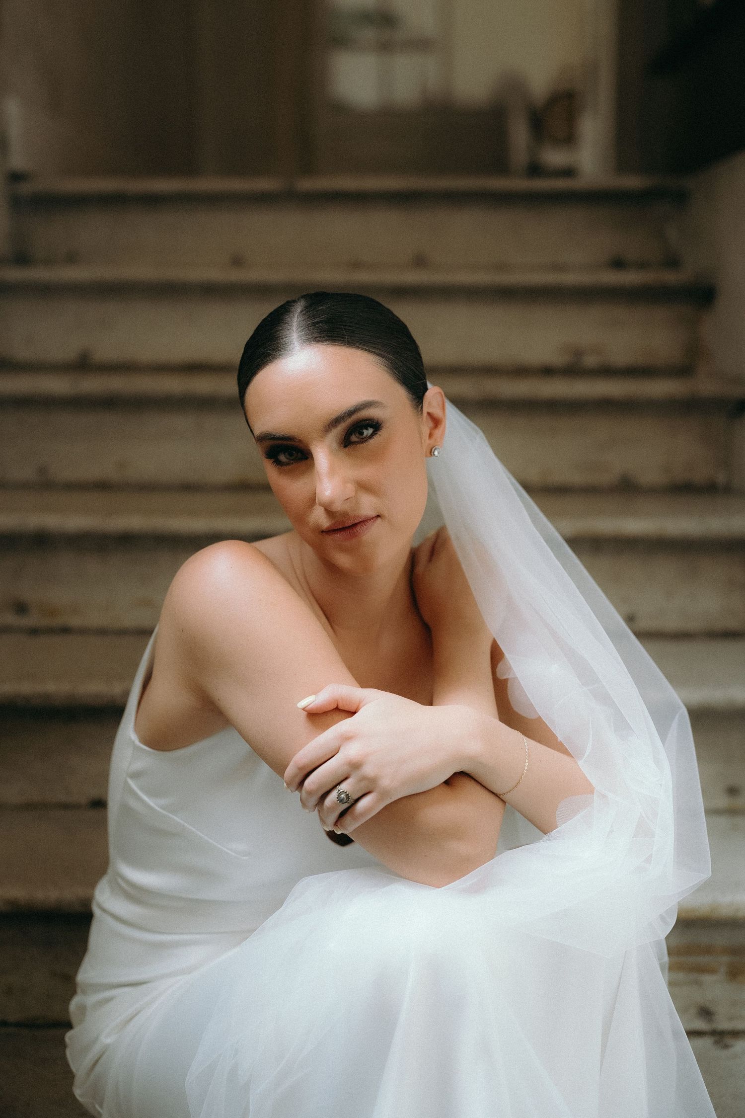 Artistic bridal portrait series featuring flowing white dress and veil on stone steps.