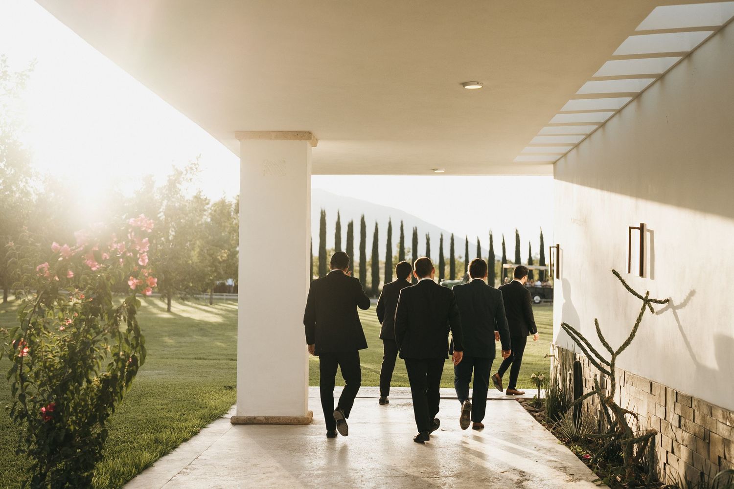 Modern architectural walkway with people silhouettes against bright sunlight.