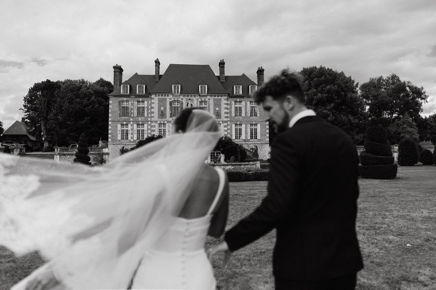 Wide landscape shots of a stately manor house with people celebrating on its grounds.