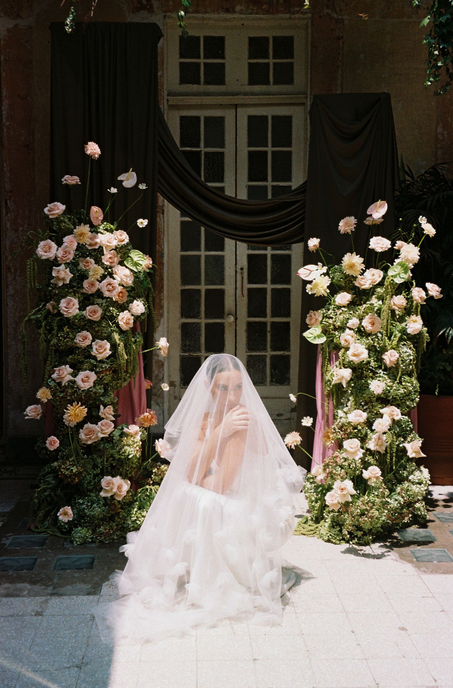 Wedding ceremony backdrop with lush pink rose arrangements framing entrance.
