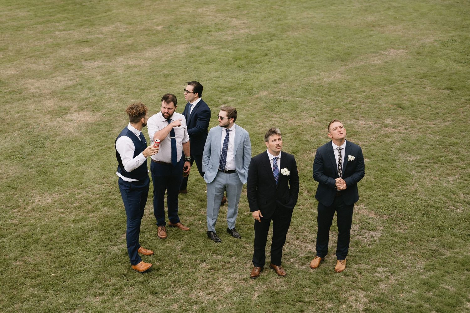 Wedding guests gathered on a lush green lawn for group photos.