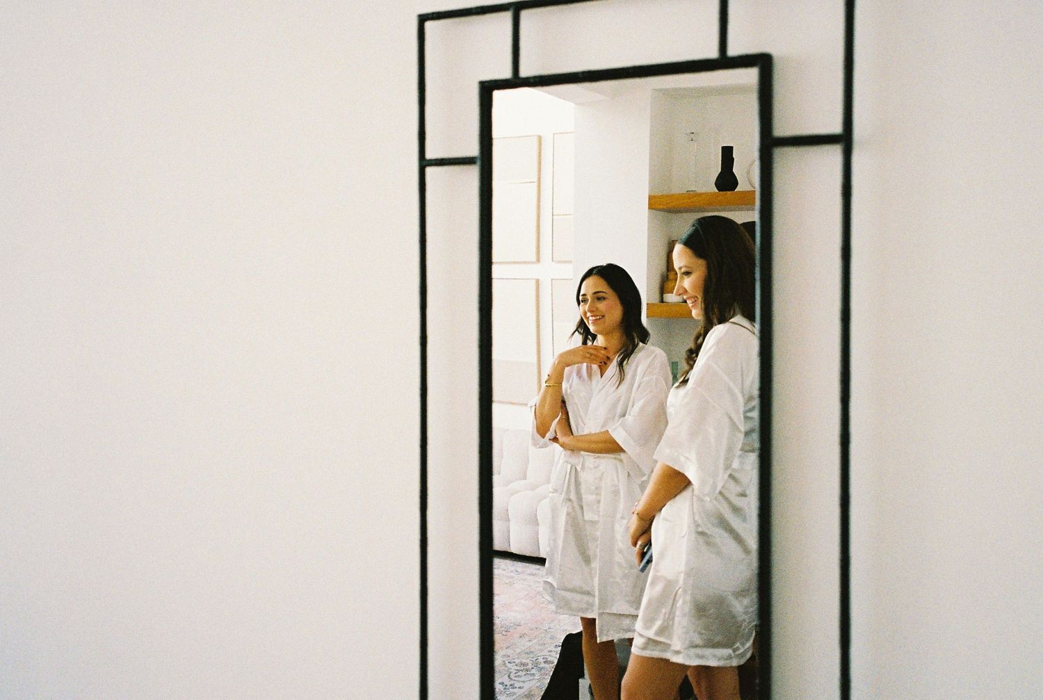 Getting ready moments captured through minimalist white framed mirrors.